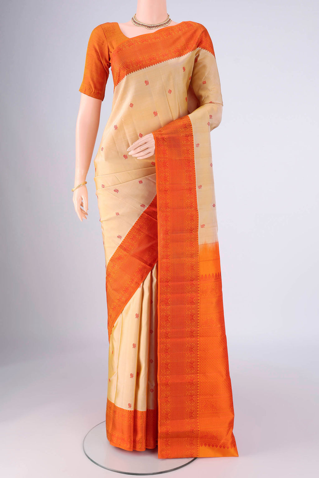 Beige Kanchipuram Silk Saree with Thread Butta on the body and Thread Border.  displayed on a mannequin