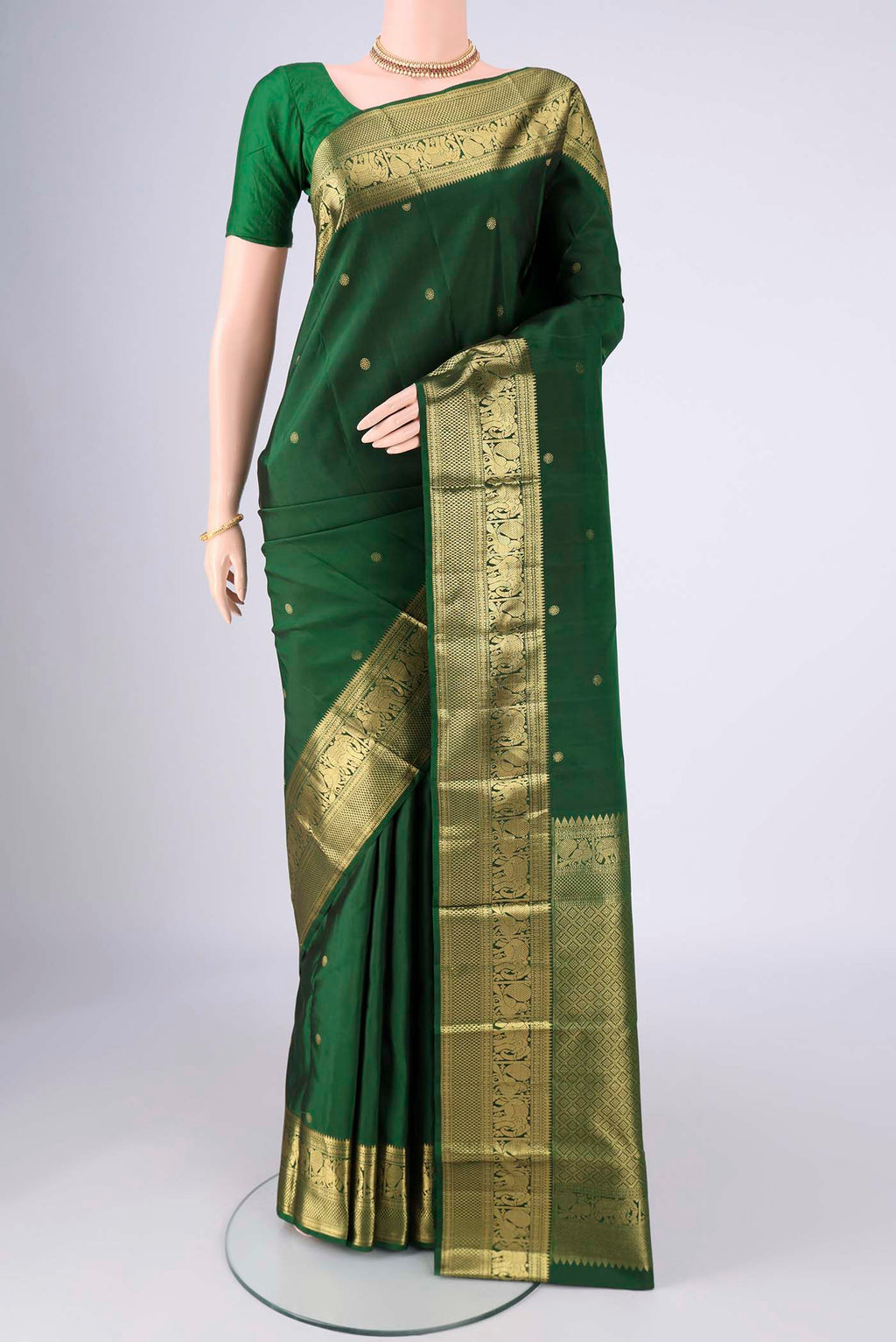 Bottle Green Kanchipuram Saree with Zari Butta on the body and Zari Border.  displayed on a mannequin