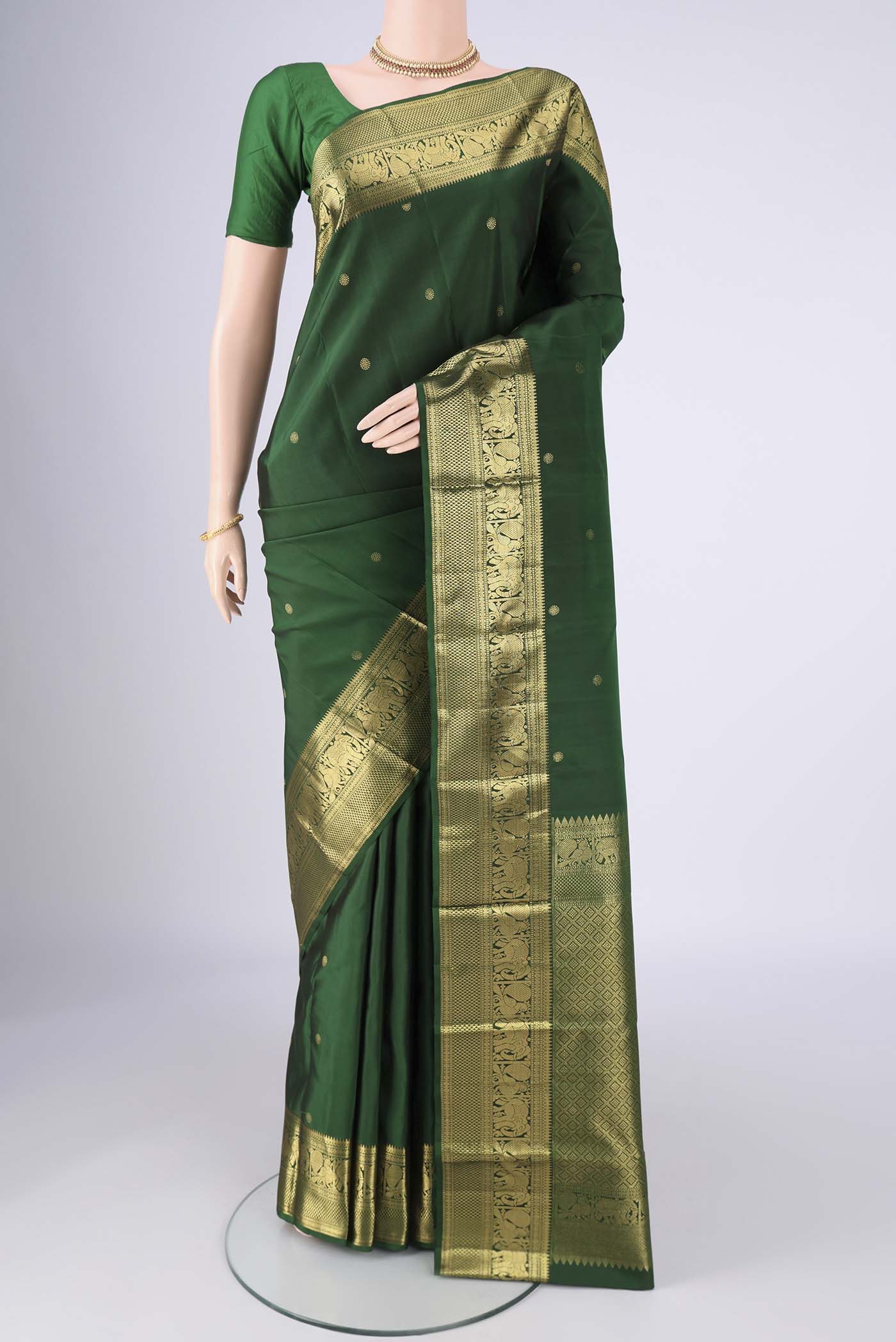 Bottle Green Kanchipuram Saree with Zari Butta on the body and Zari Border.  displayed on a mannequin