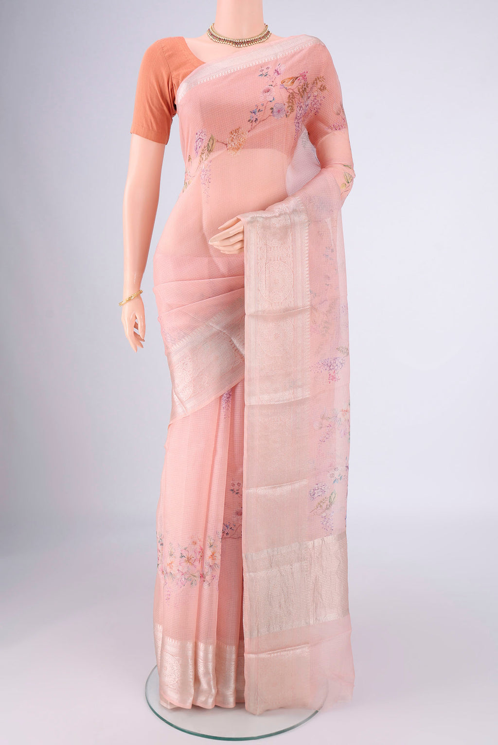 Peach Kota Silk Saree with Floral Print on the body and Zari Border.  displayed on a mannequin
