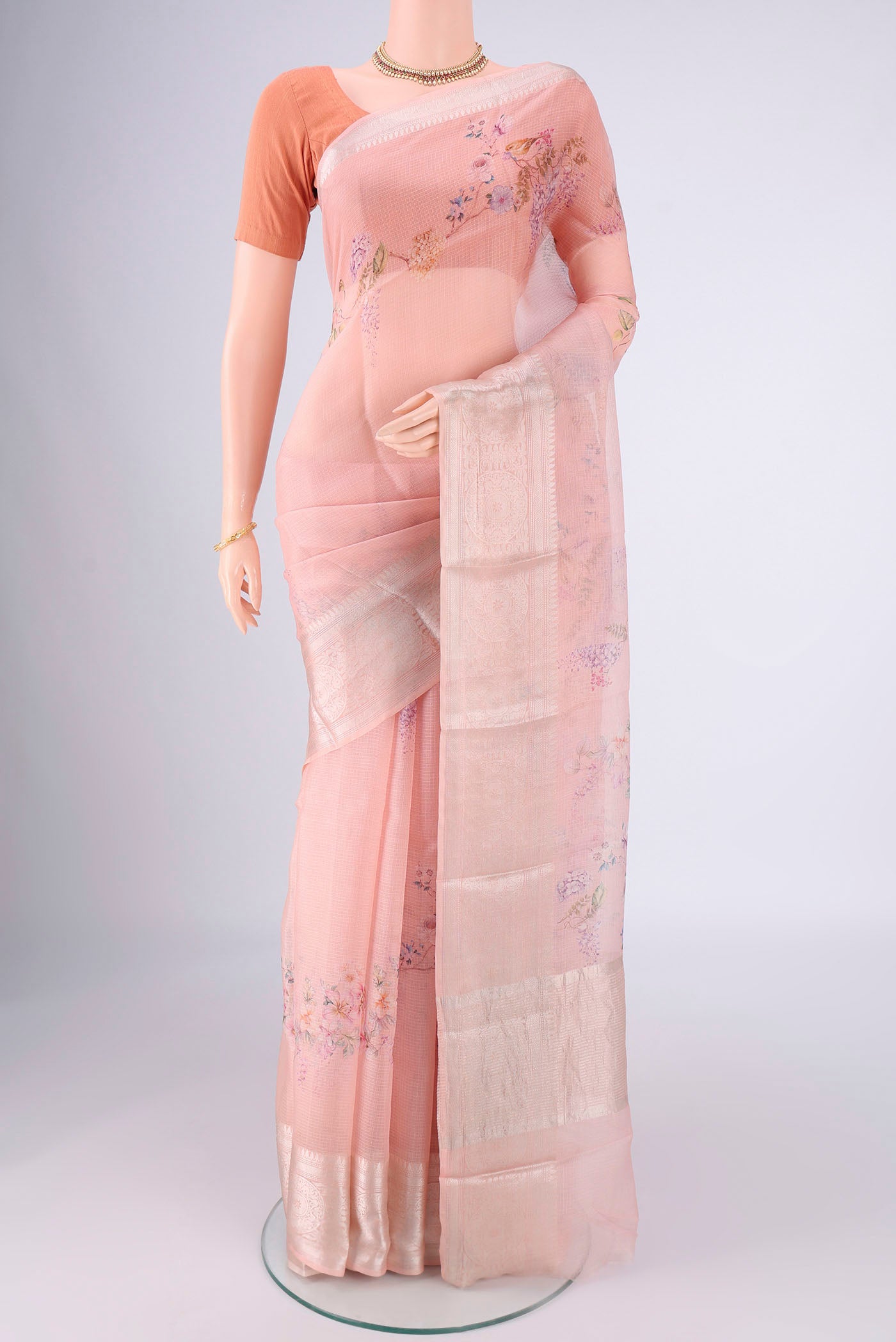 Peach Kota Silk Saree with Floral Print on the body and Zari Border.  displayed on a mannequin