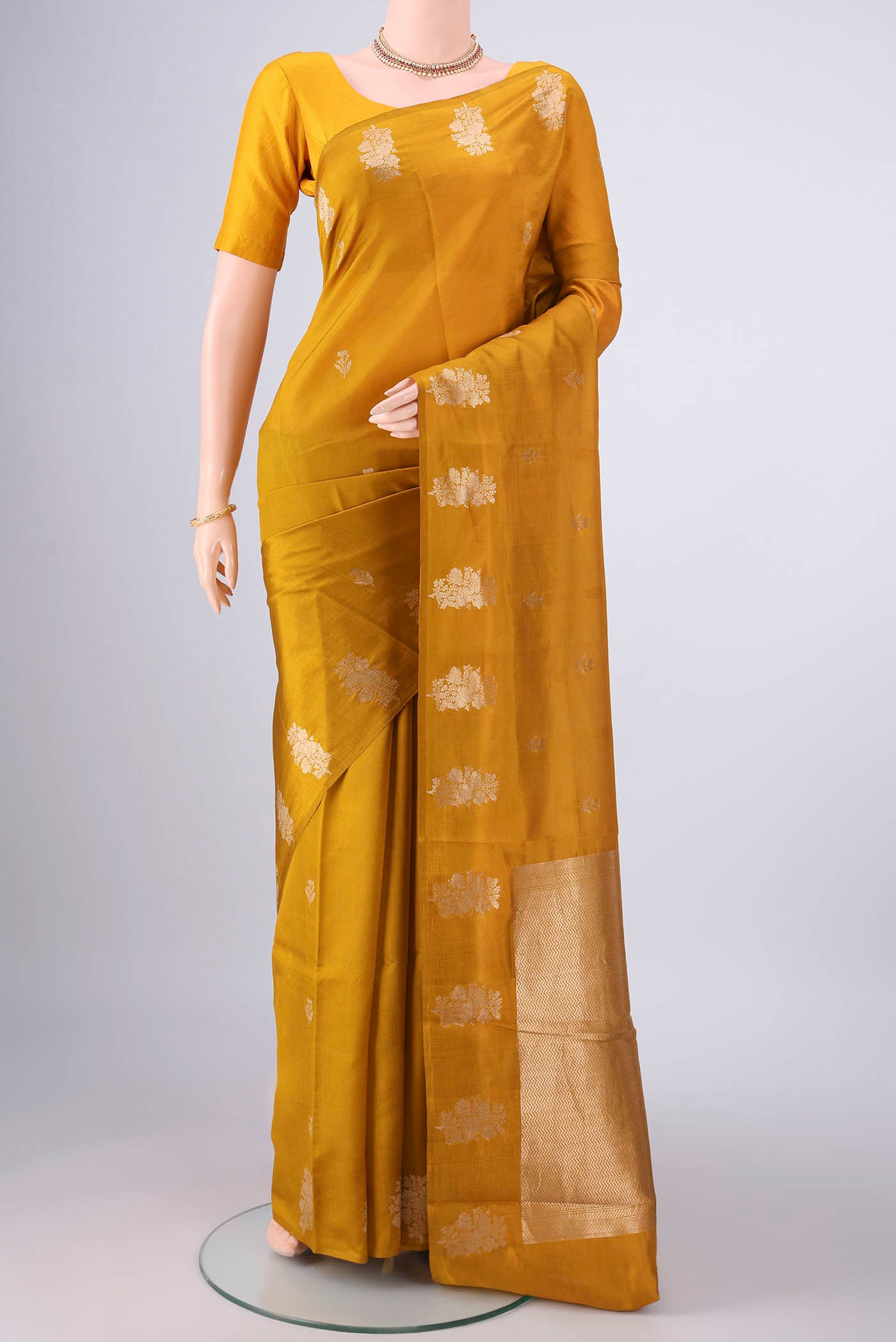 Mustard Banarasi Katan Silk Saree with Zari Butta on the body and Plain Border.  displayed on a mannequin