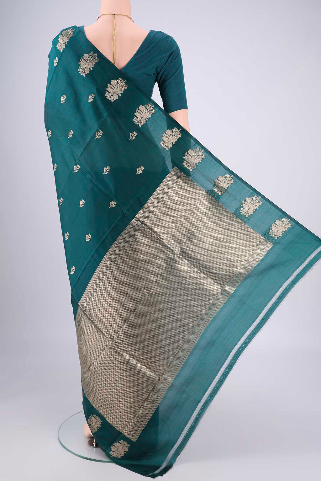 Flat view of Teal Banarasi Katan Silk Saree with Zari Butta on the body and Plain Border. 