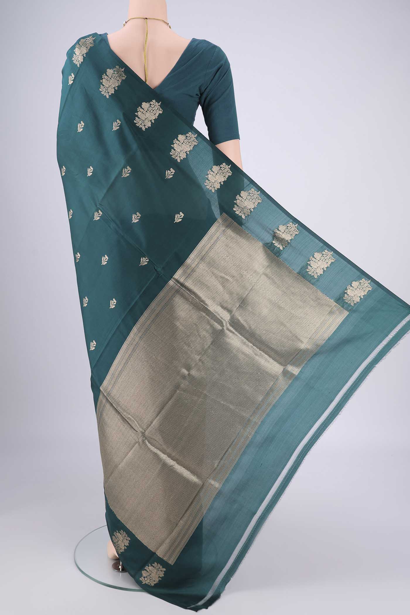Flat view of Teal Banarasi Katan Silk Saree with Zari Butta on the body and Plain Border. 
