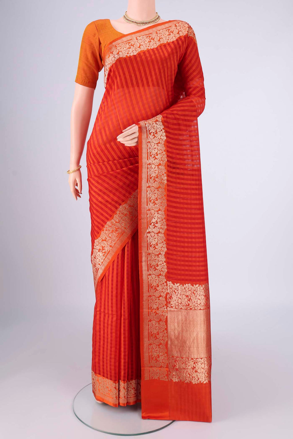 Orange Organza Silk Saree with Stripes on the body and Silk Border.  displayed on a mannequin