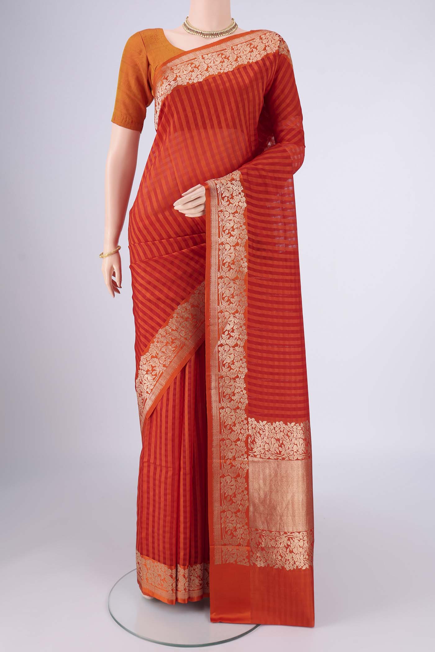 Orange Organza Silk Saree with Stripes on the body and Silk Border.  displayed on a mannequin