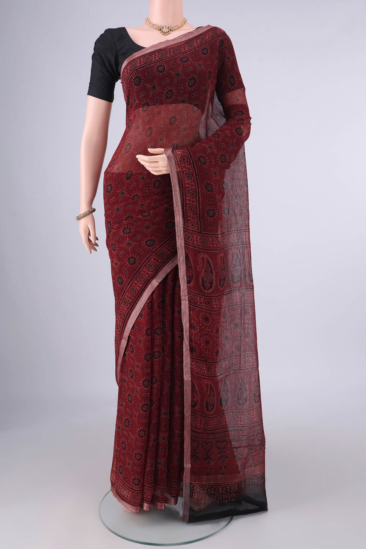Maroon Kota Cotton Saree with Ajrakh Print on the body and Zari Border.  displayed on a mannequin