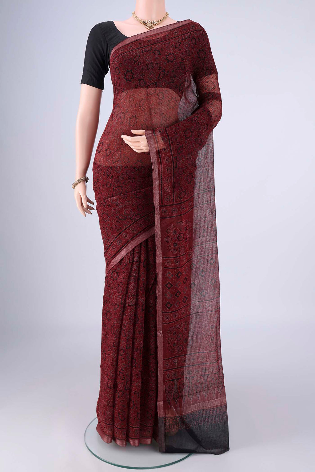 Maroon Kota Cotton Saree with Ajrakh Print on the body and Zari Border.  displayed on a mannequin