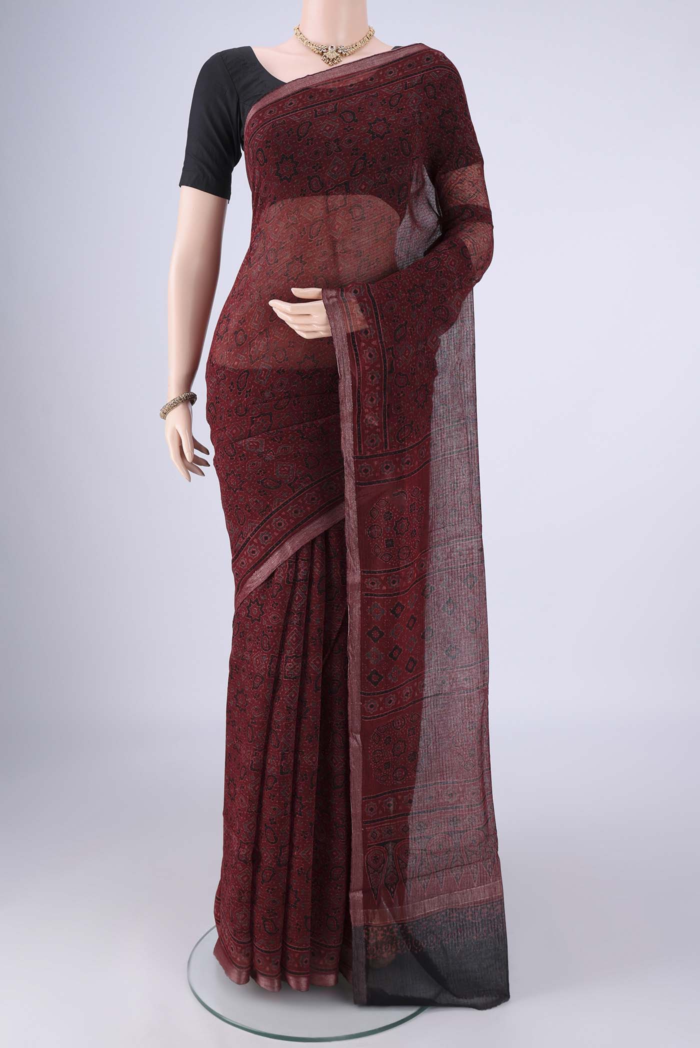 Maroon Kota Cotton Saree with Ajrakh Print on the body and Zari Border.  displayed on a mannequin