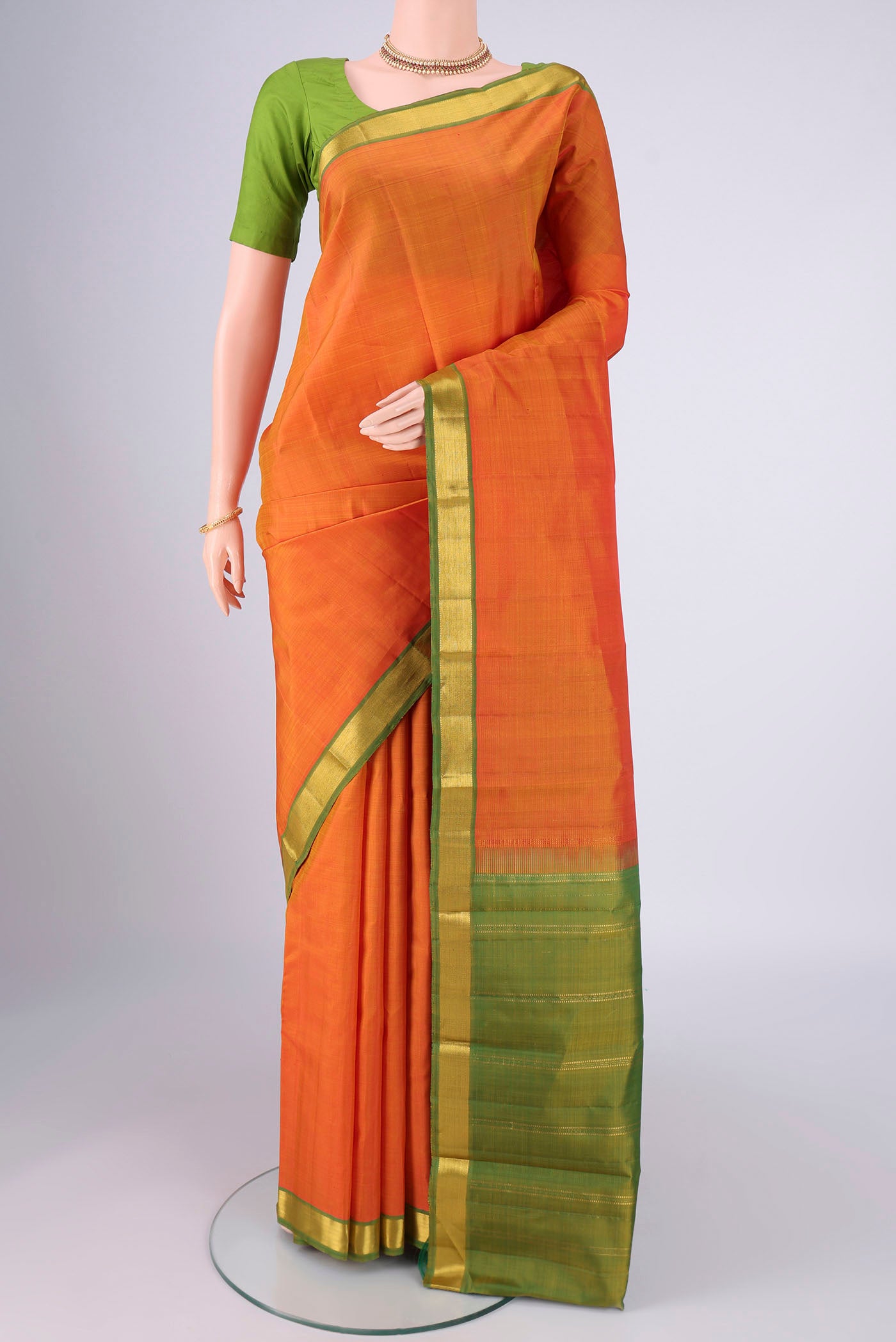 Brick Orange Kanjivaram Silk Saree with Plain Body and Zari Border.  displayed on a mannequin