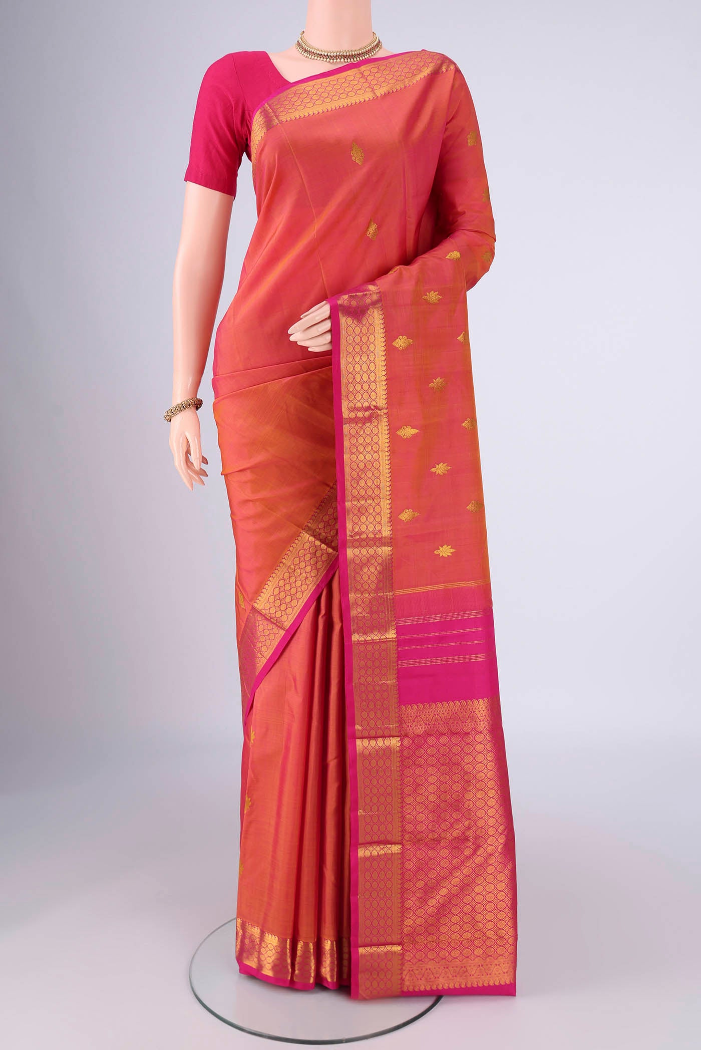 Pinkish Yellow Dual Tone Kanchipuram Silk Saree with Zari Butta on the body and Zari Border.  displayed on a mannequin