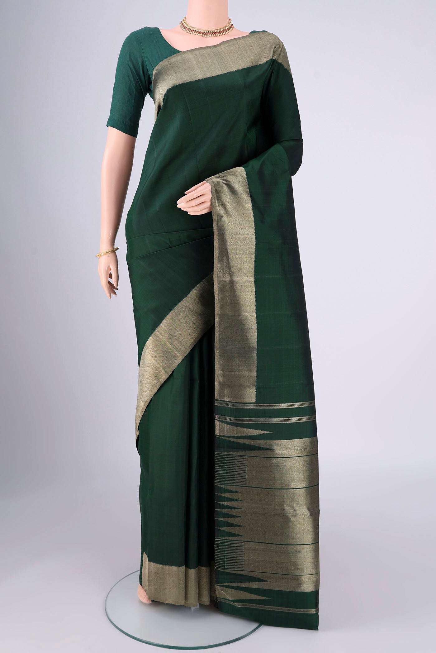 Bottle Green Kanjivaram Silk Saree with Plain Body and Zari Border.  displayed on a mannequin