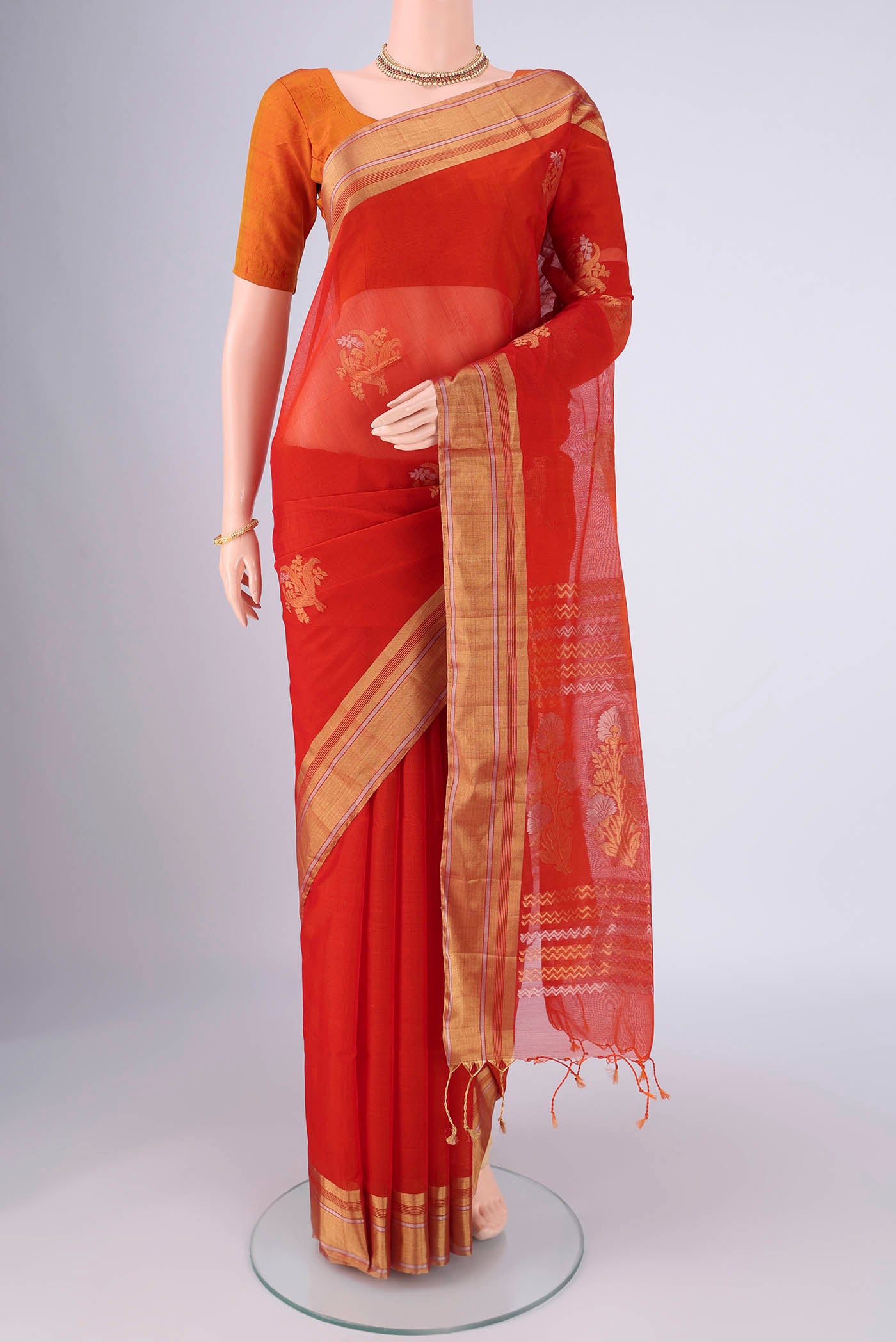 Orange Silk Cotton Saree with Zari Butta on the body and Zari Border.  displayed on a mannequin