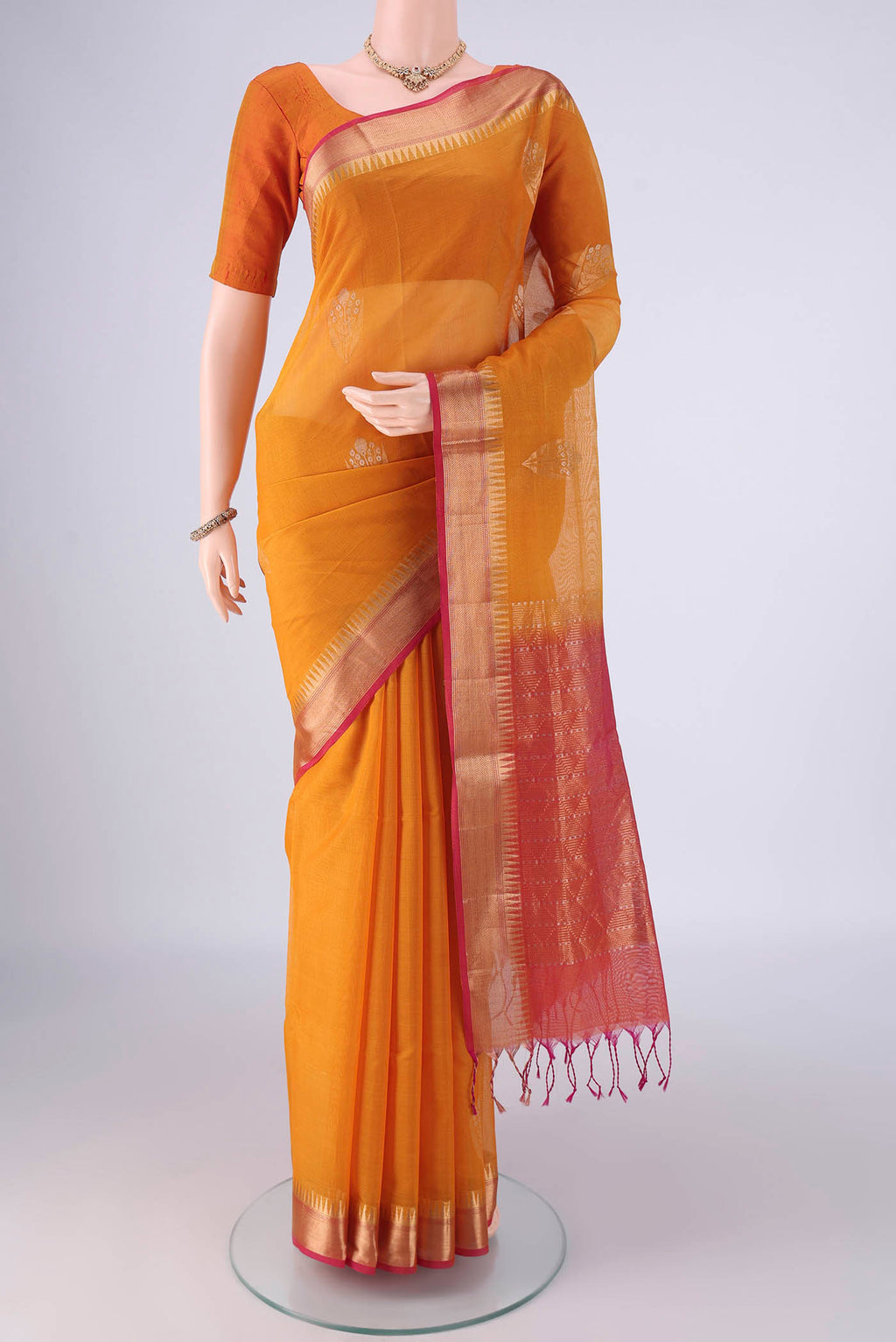 Mustard Kora Cotton Saree with Zari Butta on the body and Zari Border.  displayed on a mannequin