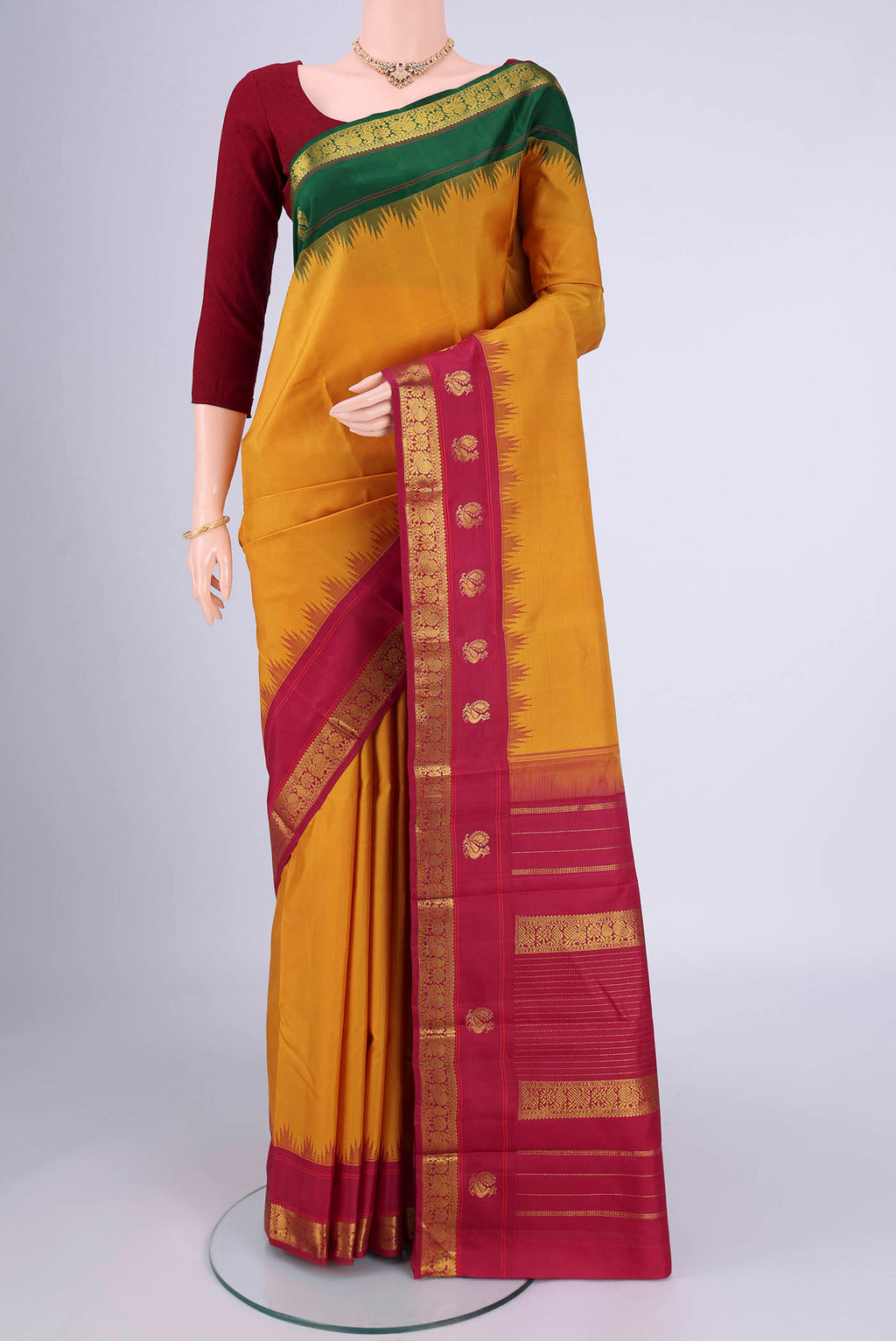 Pure Silk Pure Zari Mustard Kanjivaram Saree with Plain Body and Ganga Jamuna Border.  displayed on a mannequin