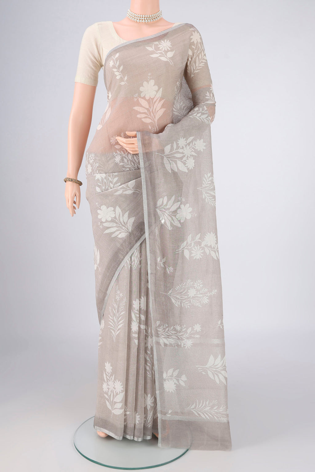 Grey Linen Saree with Floral Print on the body and Zari Border.  displayed on a mannequin
