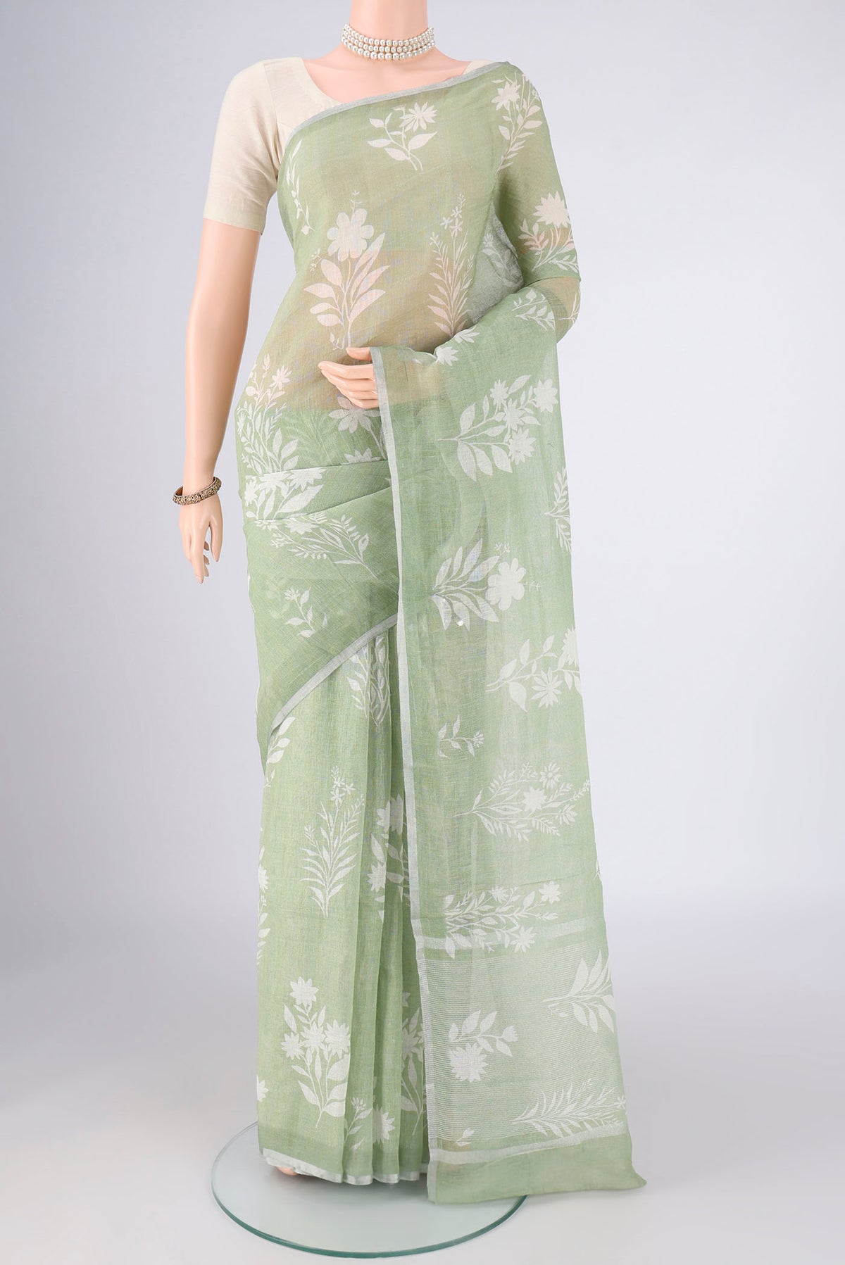 Light Green Linen Saree with Floral Print on the body and Zari Border.  displayed on a mannequin