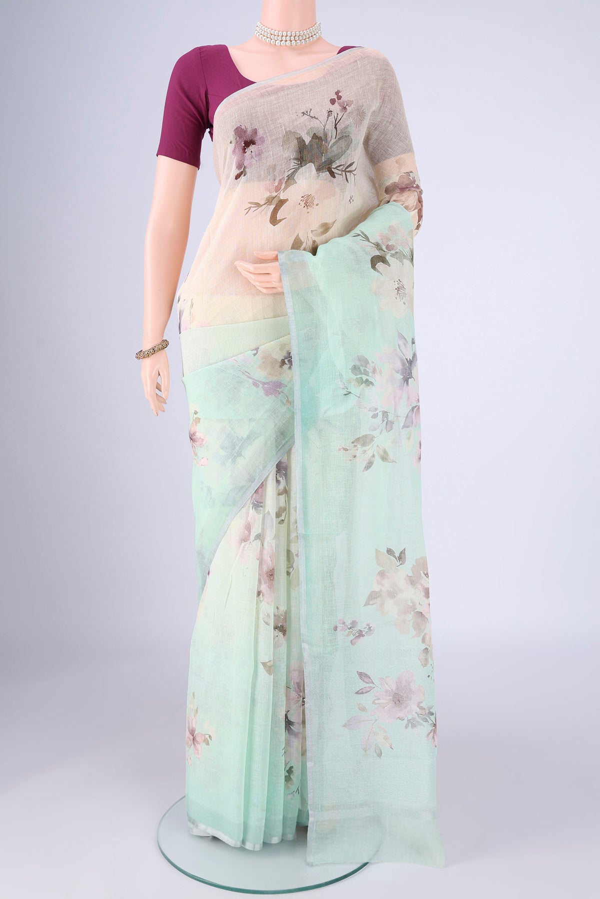 Mint Green Linen Saree with Floral Print on the body and Zari Border.  displayed on a mannequin