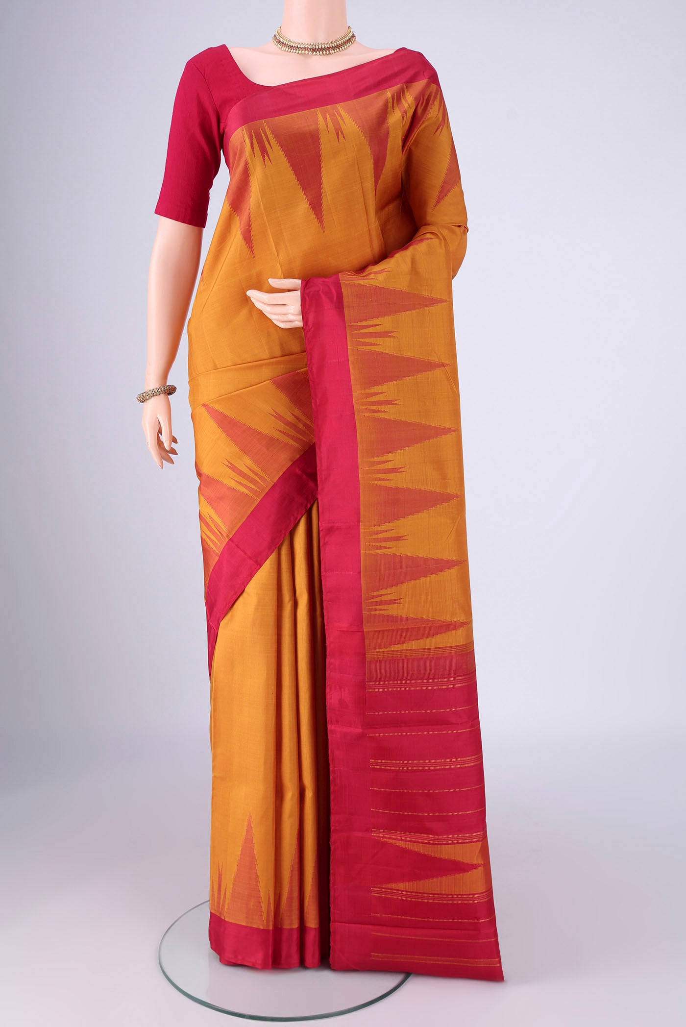 Mustard Kanchipuram Silk Saree with Plain Body and Temple Border.  displayed on a mannequin