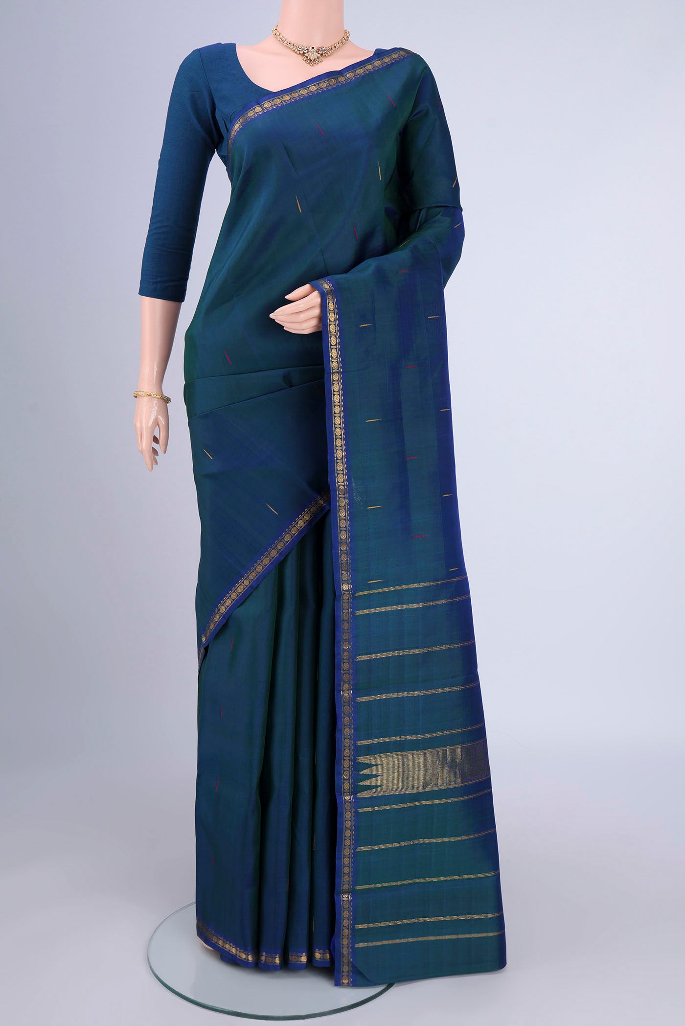Peacock Blue Kanchipuram Silk Saree with Zari Butta on the body and Zari Border.  displayed on a mannequin