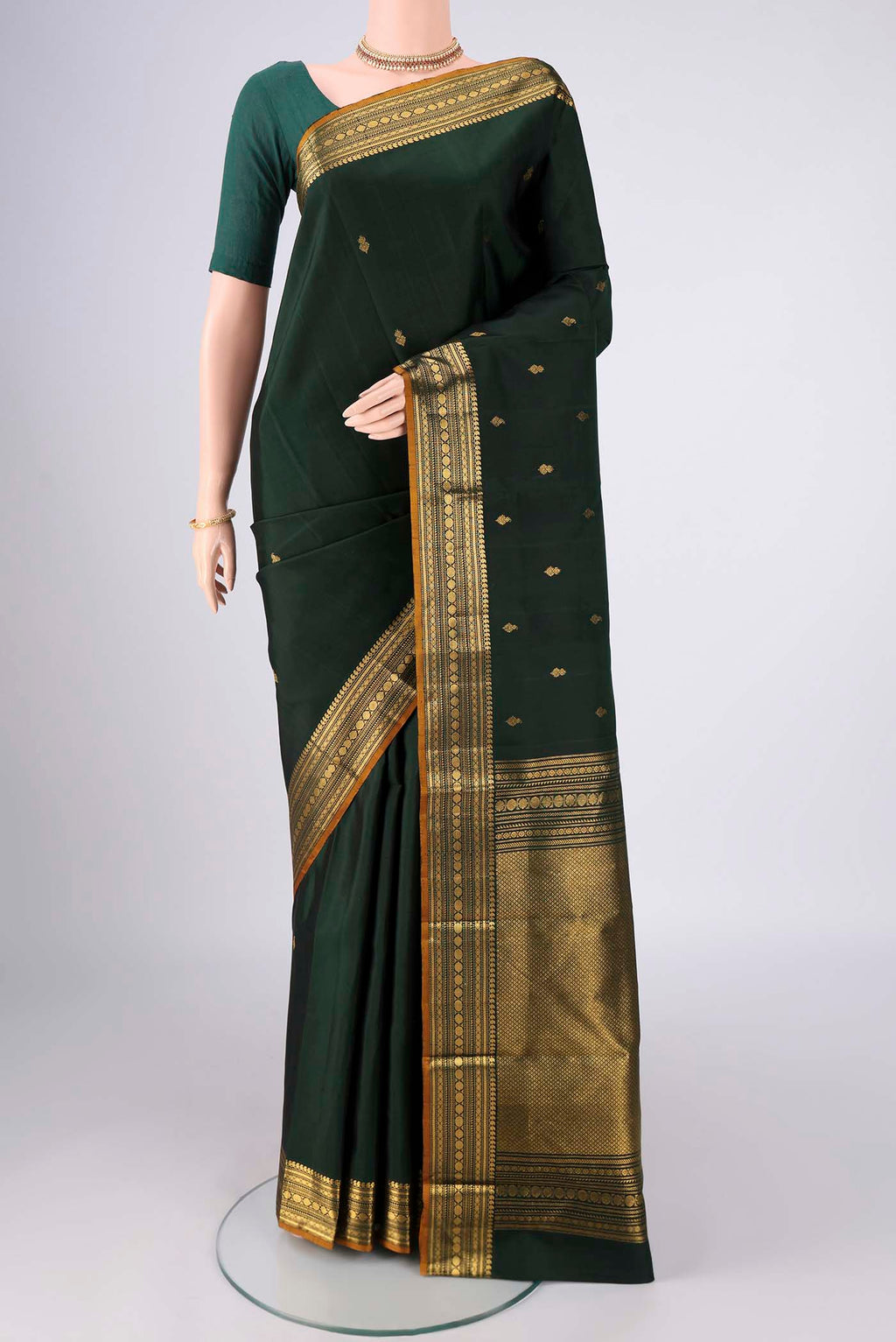 Bottle Green Kanjivaram Silk Saree with Zari Butta on the body and Zari Border.  displayed on a mannequin