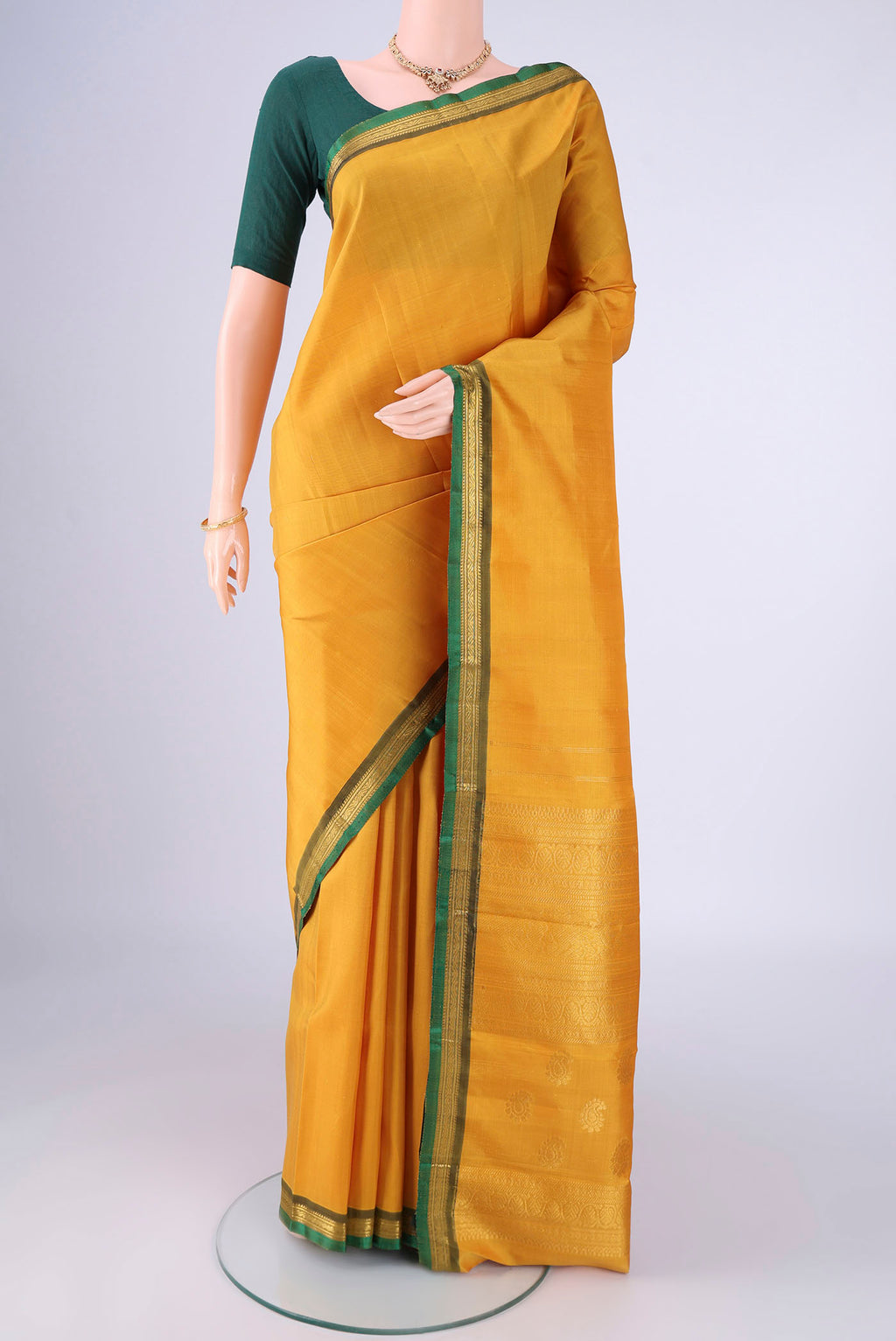 Mustard Kanjivaram Silk Saree with Plain Body and Zari Border.  displayed on a mannequin