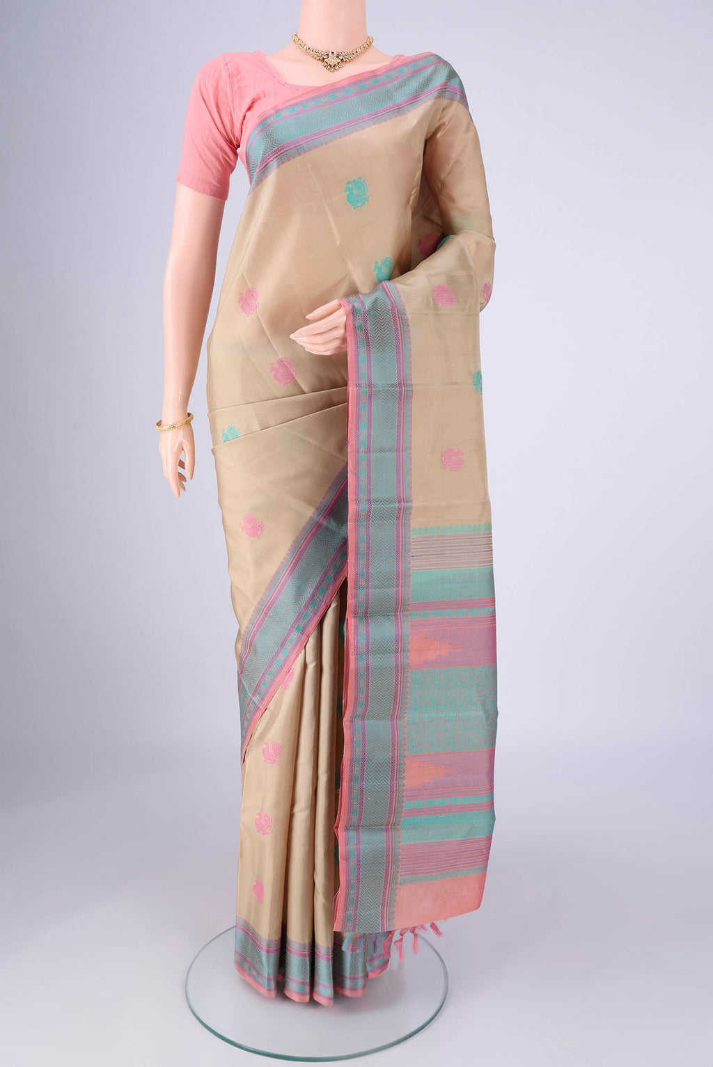 Beige Kanchipuram Silk Saree with Thread Butta on the body and Thread Border.  displayed on a mannequin