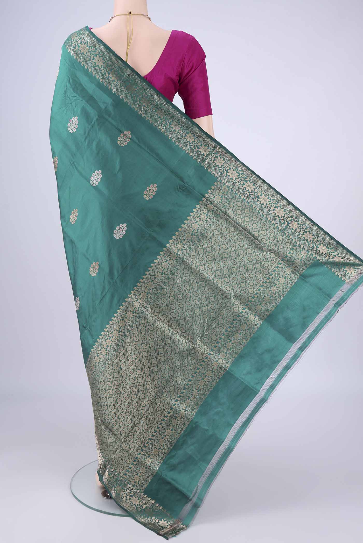 Flat view of Teal Banarasi Katan Silk Saree with Zari And Thread Butta on the body and Zari Border. 