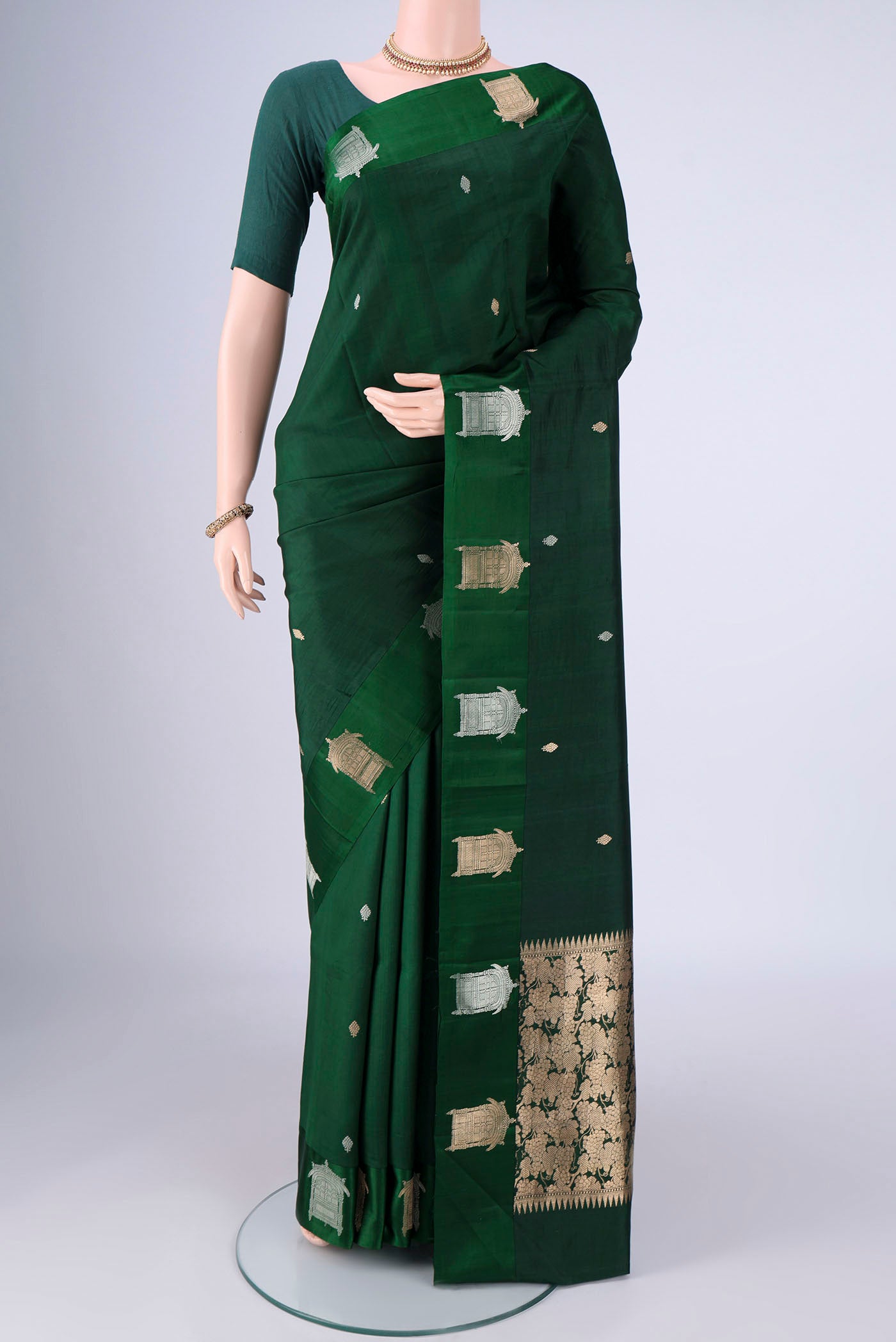 Bottle Green Banarasi Katan Silk Saree with Zari Butta on the body and Satin Border.  displayed on a mannequin