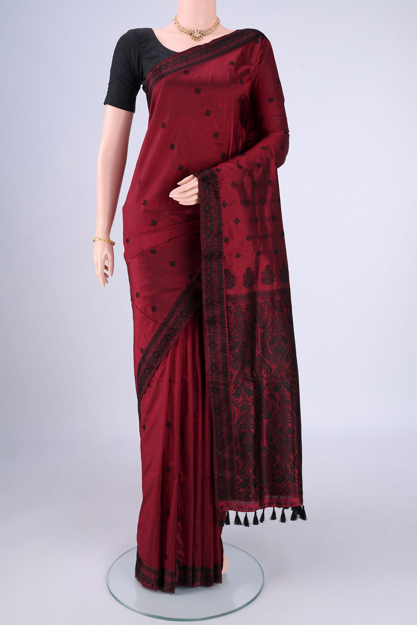 Maroon Assam Silk Saree with Thread Butta on the body and Thread Border.  displayed on a mannequin