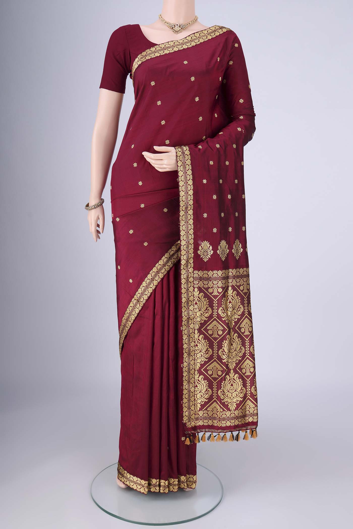 Maroon Assam Silk Saree with Thread Butta on the body and Thread Border.  displayed on a mannequin