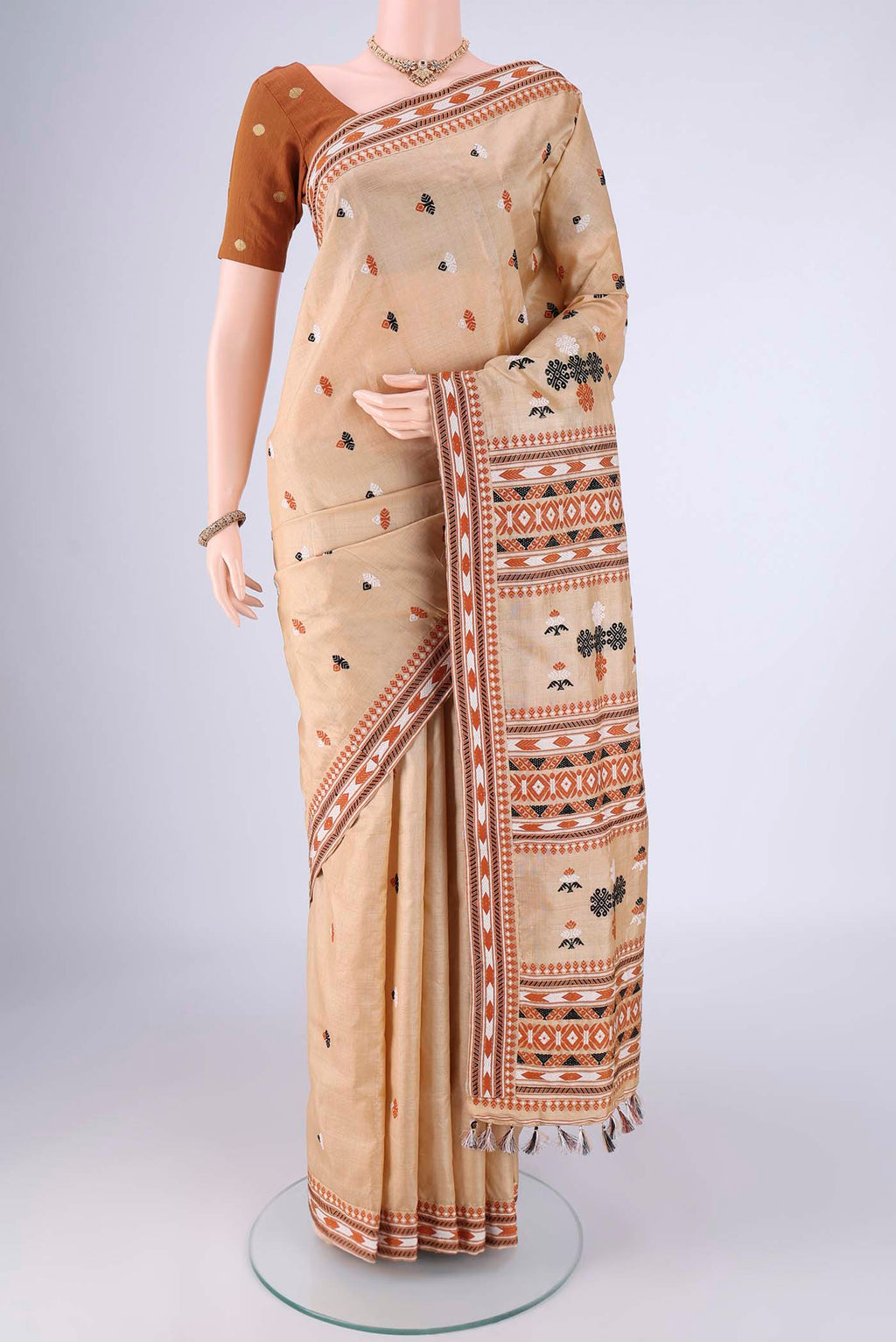 Beige Assam Silk Saree with Thread Butta on the body and Thread Border.  displayed on a mannequin