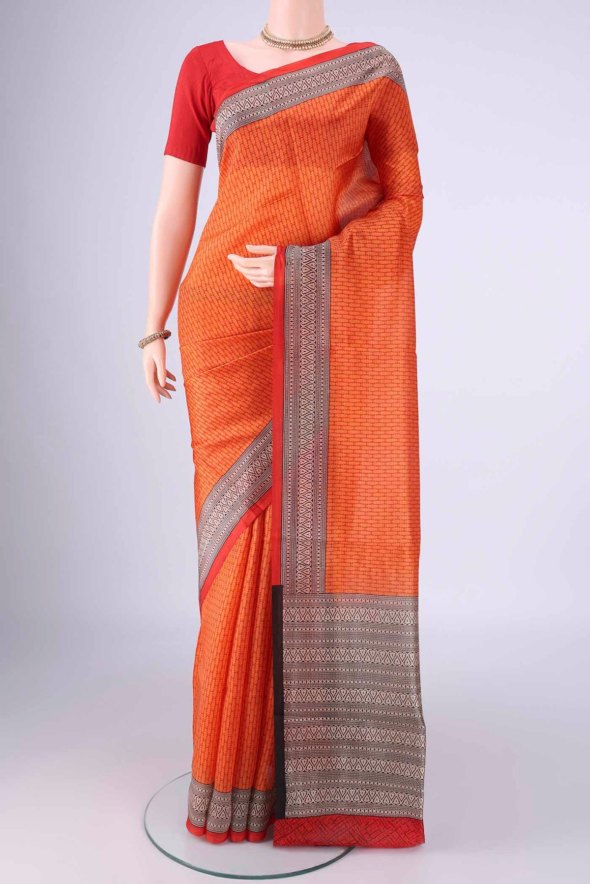 Orange Printed Silk Saree with Printed design on the body and Printed Border.  displayed on a mannequin
