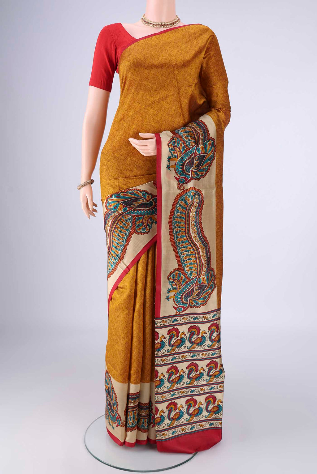 Mustard Printed Silk Saree with Printed design on the body and Plain Border.  displayed on a mannequin