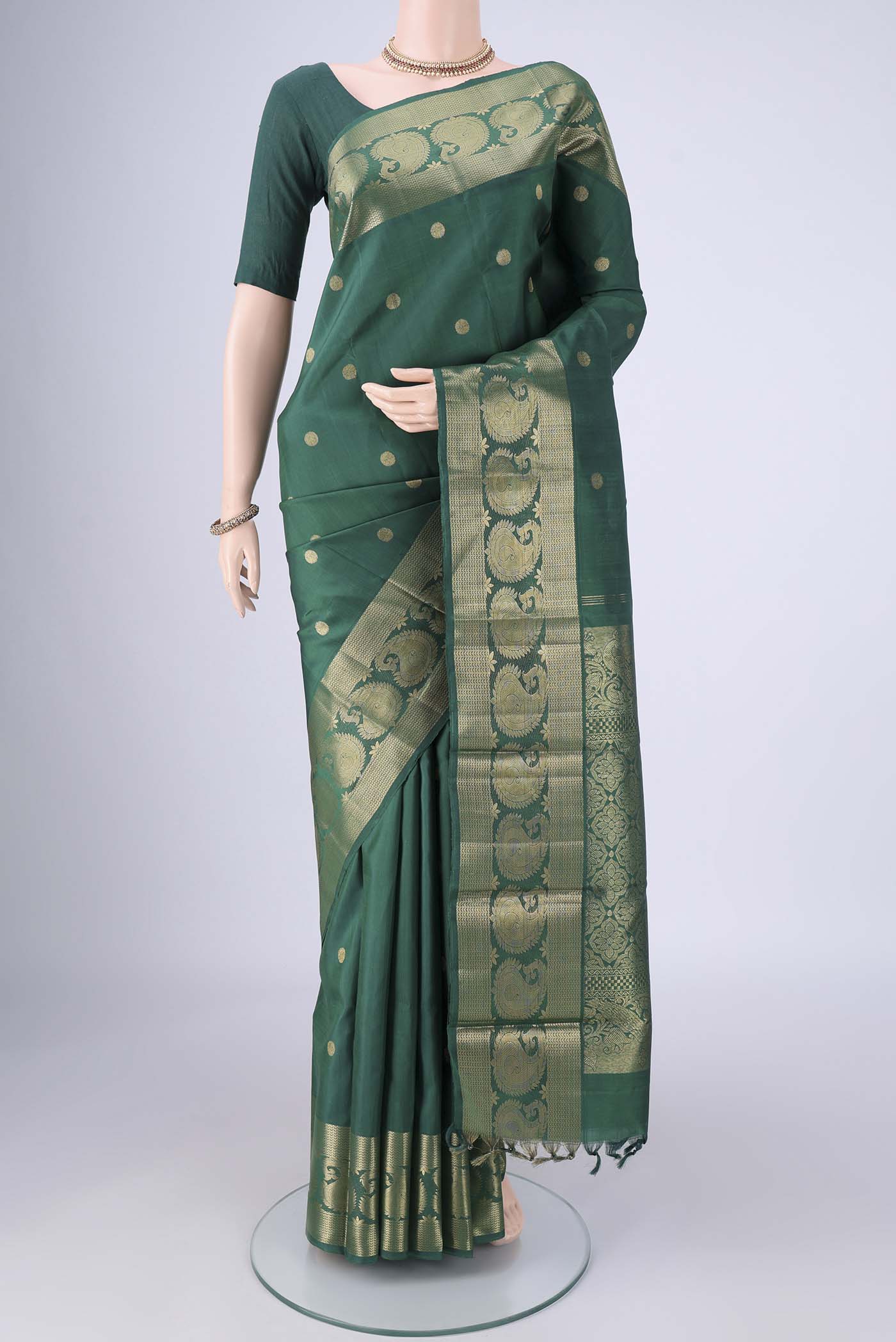 Bottle Green Kanjivaram Silk Saree with Zari Butta on the body and Zari Border.  displayed on a mannequin