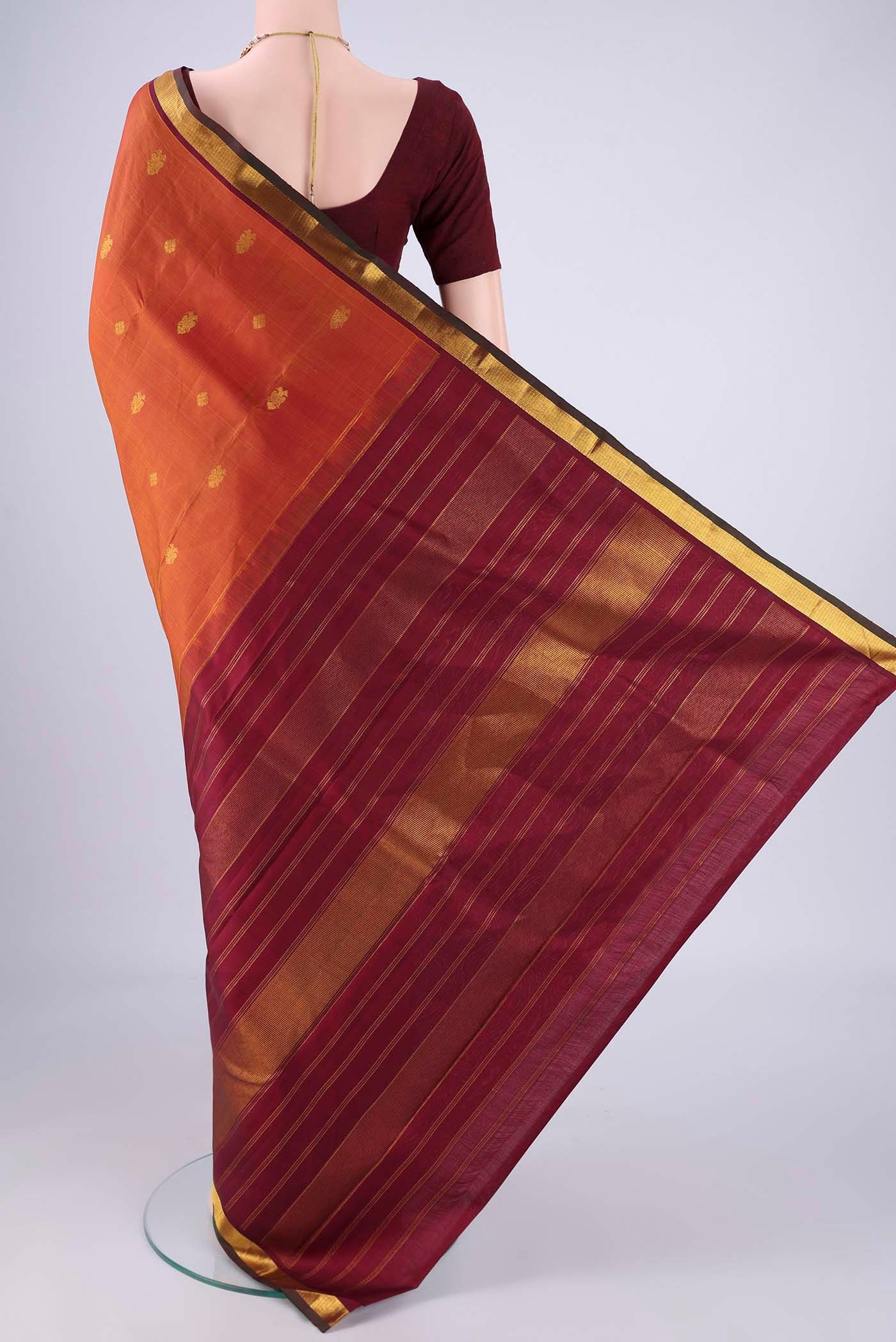 Flat view of Rust Kanchipuram Silk Saree with Zari Butta on the body and Zari Border. 