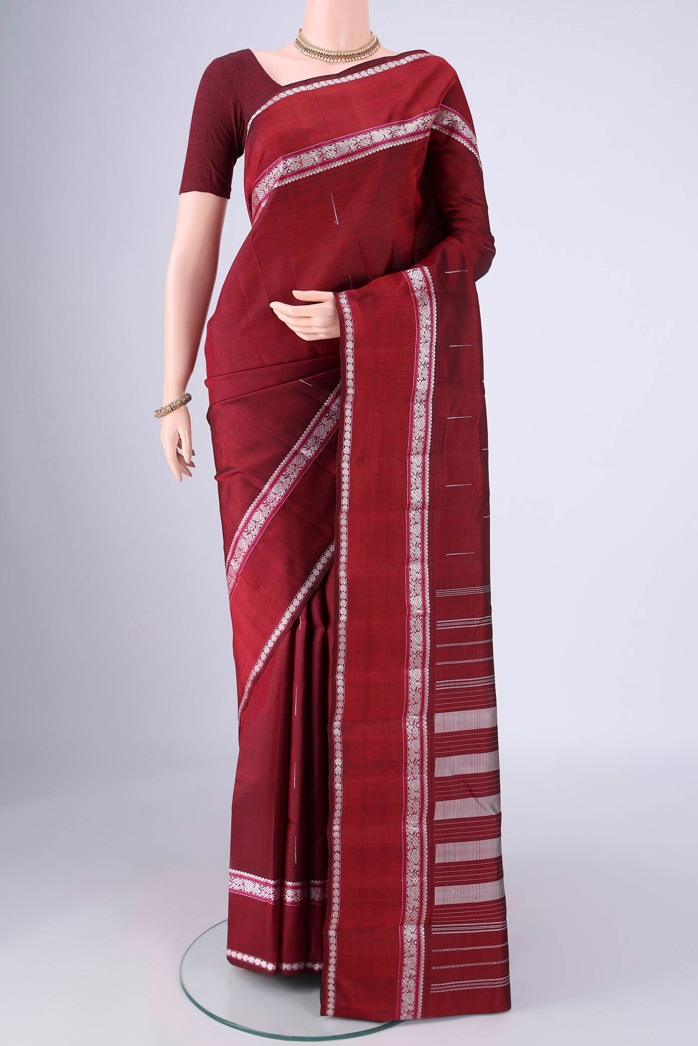 Maroon Kanchipuram Silk Saree with Thread Butta on the body and Thread Border.  displayed on a mannequin