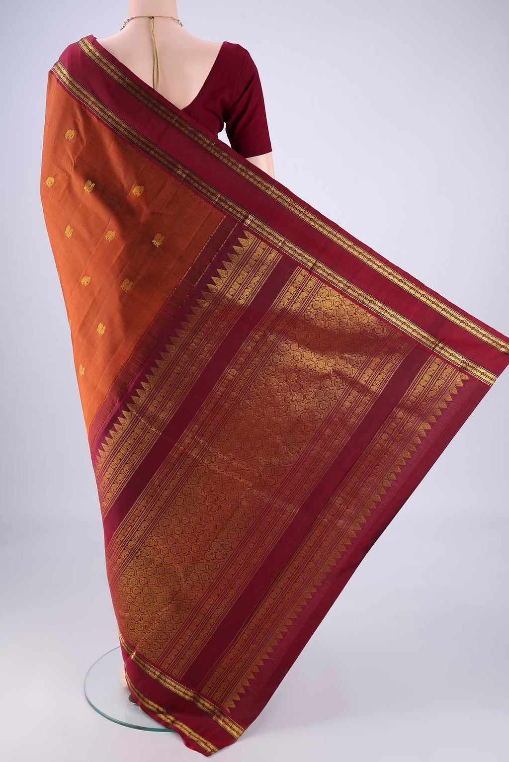 Flat view of Rust Kanchipuram Silk Saree with Zari Butta on the body and Zari Border. 
