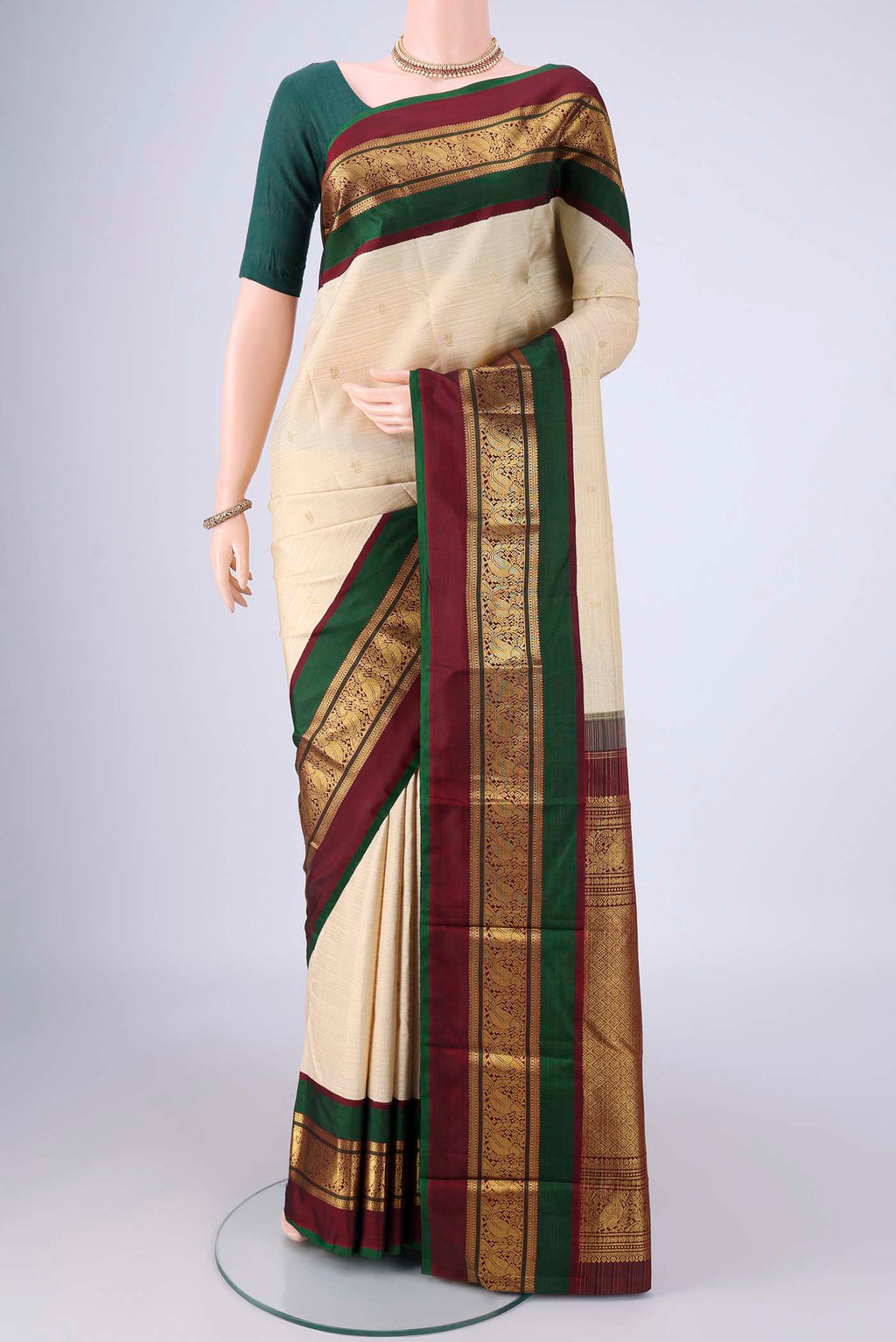Cream Kanchipuram Silk Saree with Zari Butta on the body and Zari Border.  displayed on a mannequin