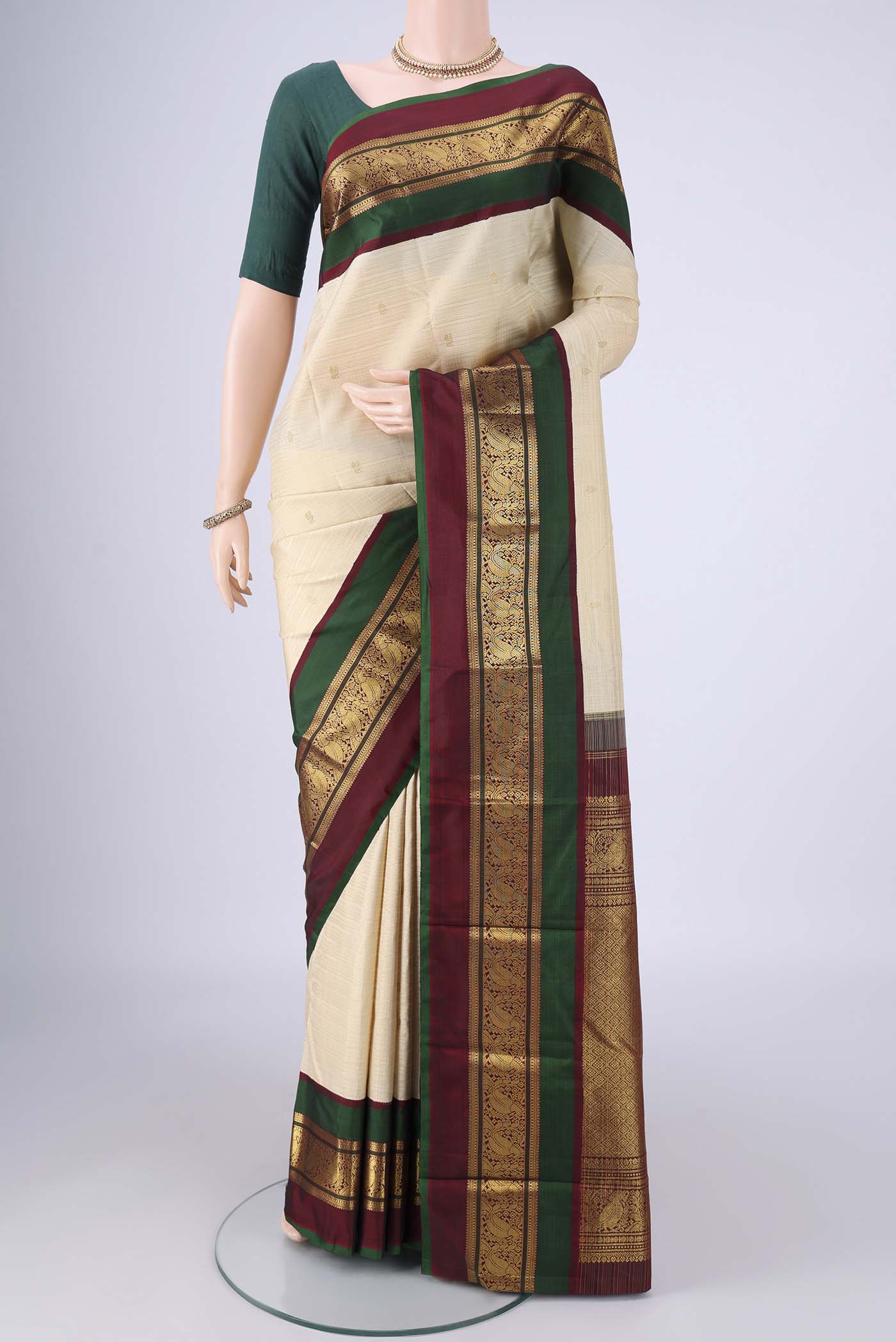 Cream Kanchipuram Silk Saree with Zari Butta on the body and Zari Border.  displayed on a mannequin