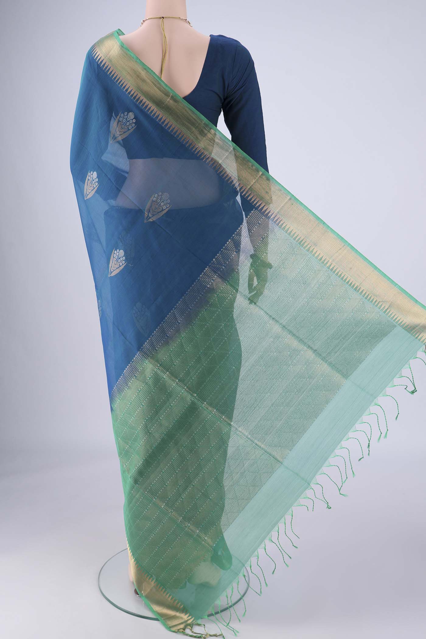 Flat view of Peacock Blue Silk Cotton Saree with Zari Butta on the body and Zari Border. 