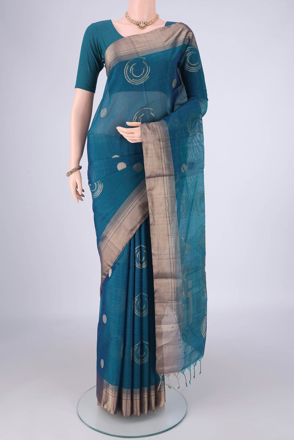 Peacock Blue Kora Cotton Saree with Zari Butta on the body and Zari Border.  displayed on a mannequin