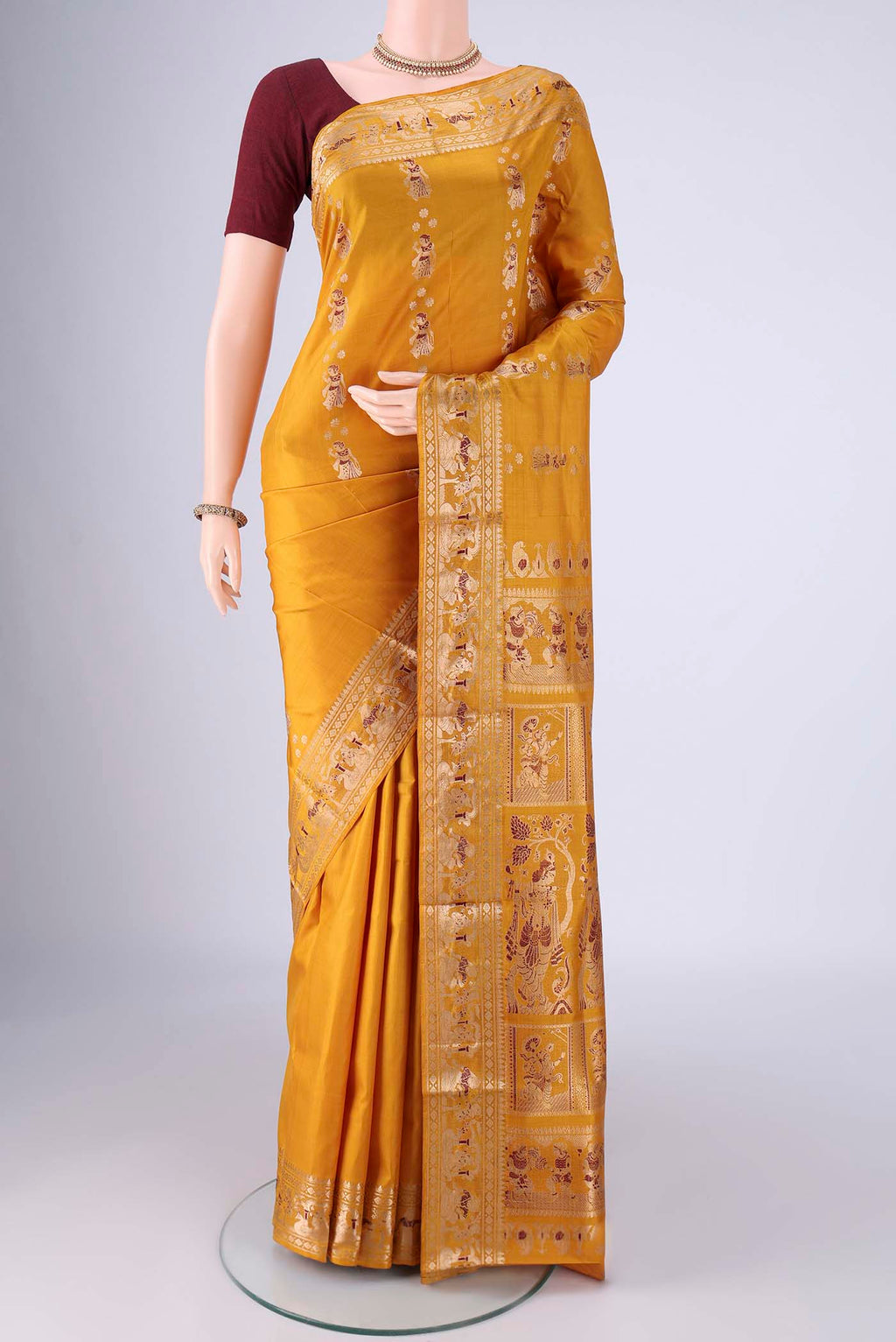 Mustard Baluchari Silk Saree with Zari And Thread Butta on the body and Zari And Thread Border.  displayed on a mannequin