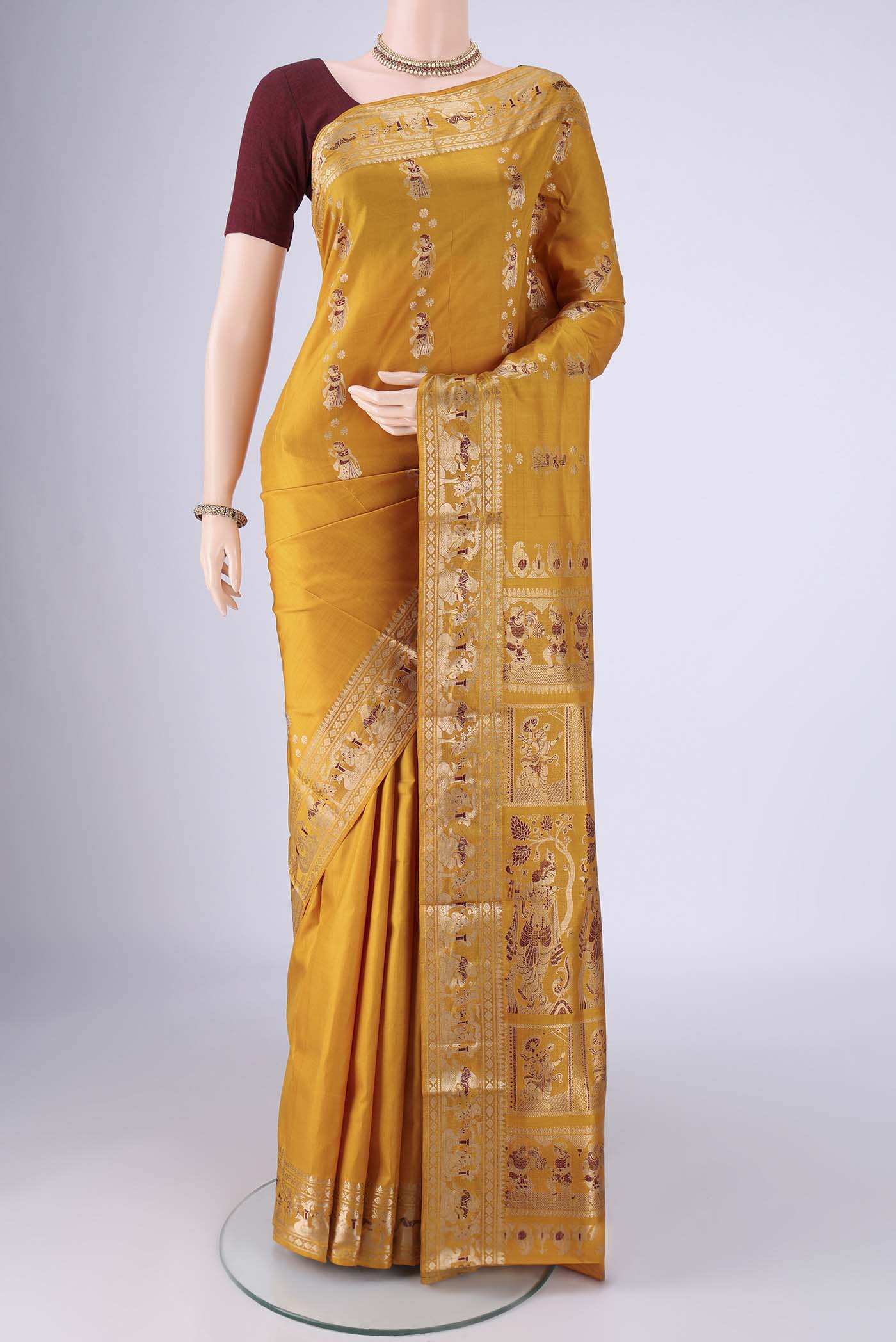 Mustard Baluchari Silk Saree with Zari And Thread Butta on the body and Zari And Thread Border.  displayed on a mannequin