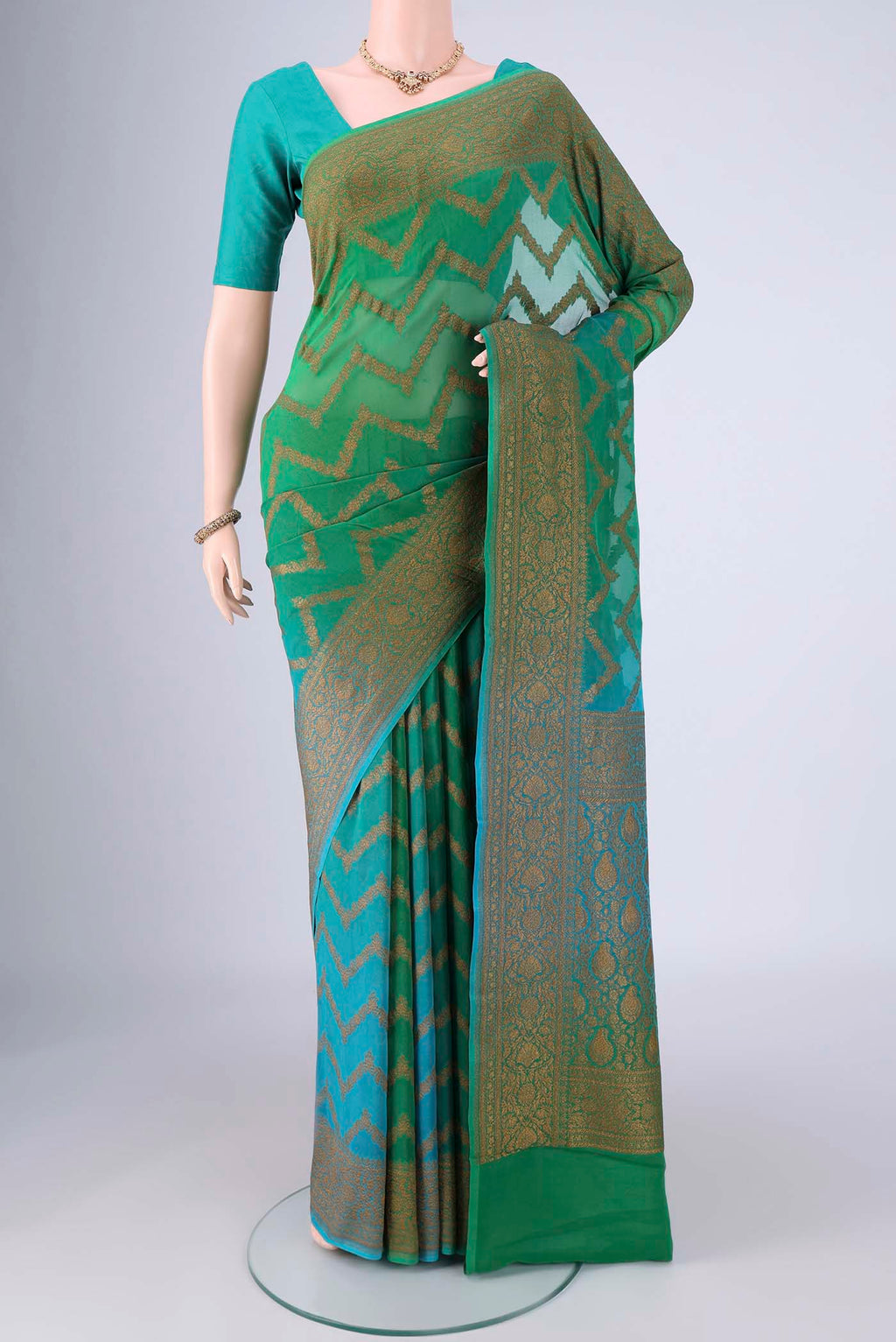 Green Banarasi Georgette Saree with Zig Zag design on the body and Zari Border.  displayed on a mannequin