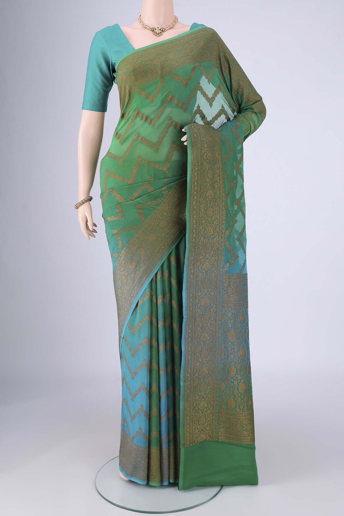 Green Banarasi Georgette Saree with Zig Zag design on the body and Zari Border.  displayed on a mannequin