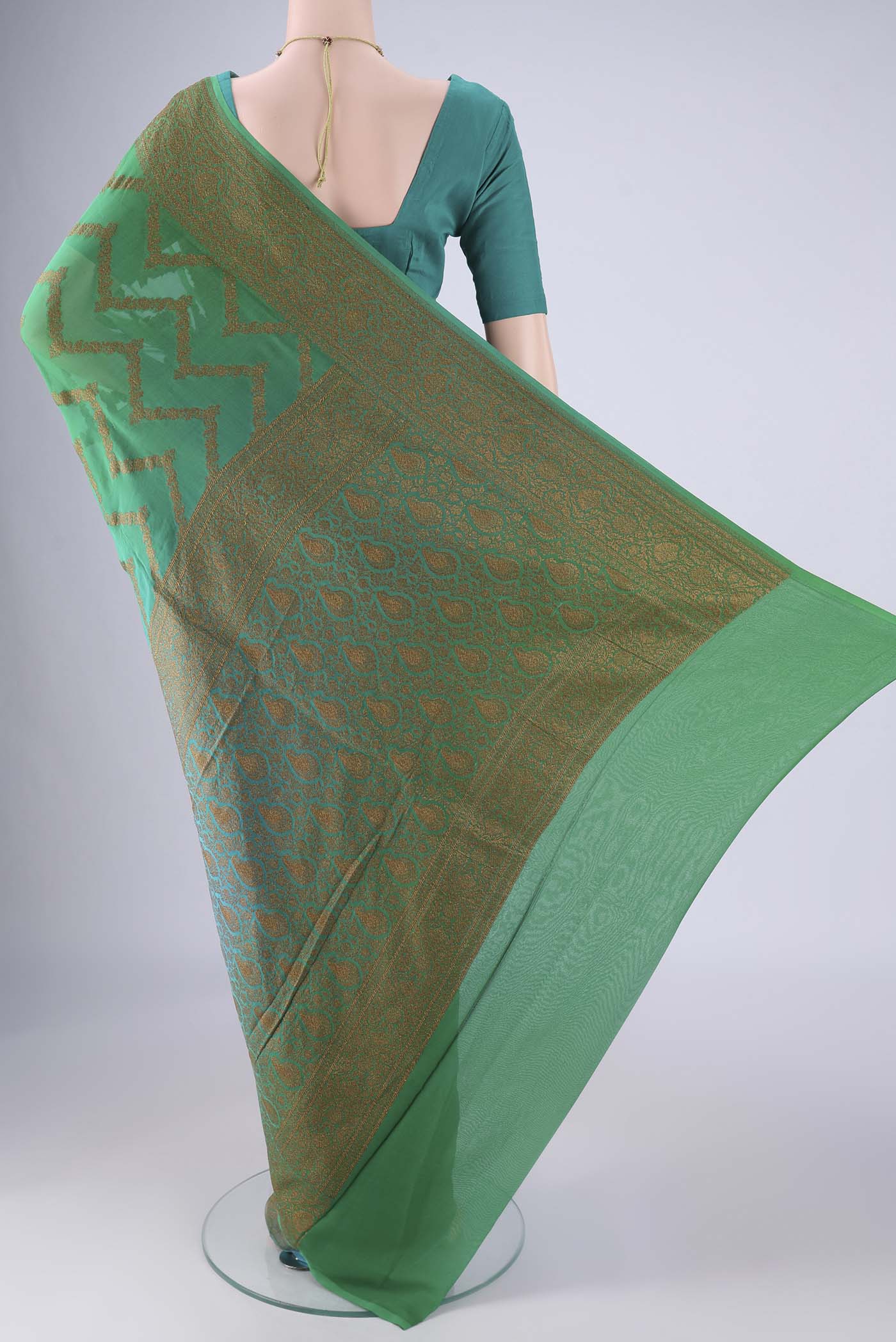 Flat view of Green Banarasi Georgette Saree with Zig Zag design on the body and Zari Border. 