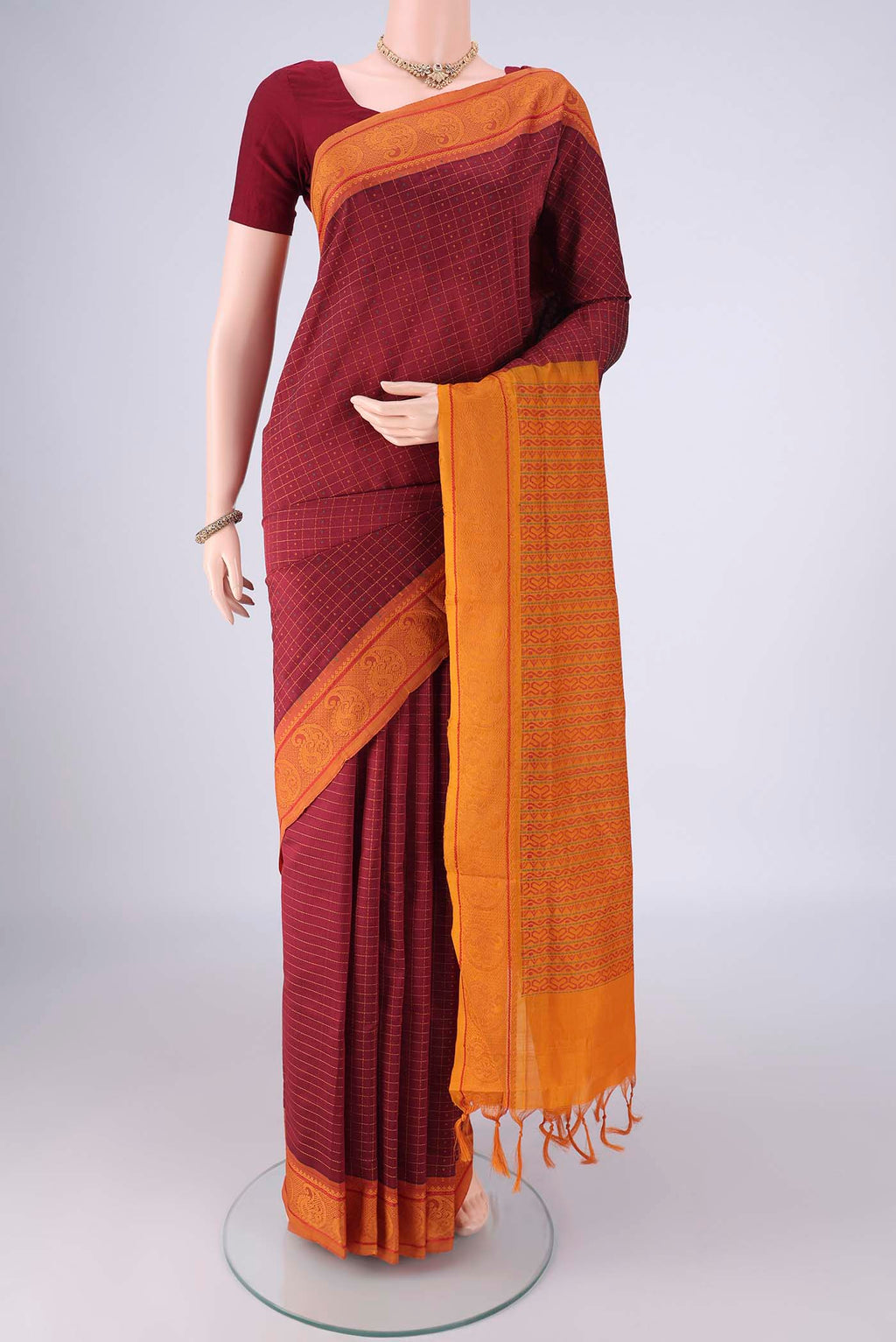 Maroon Poly Cotton Saree with Checked design on the body and Thread Border.  displayed on a mannequin