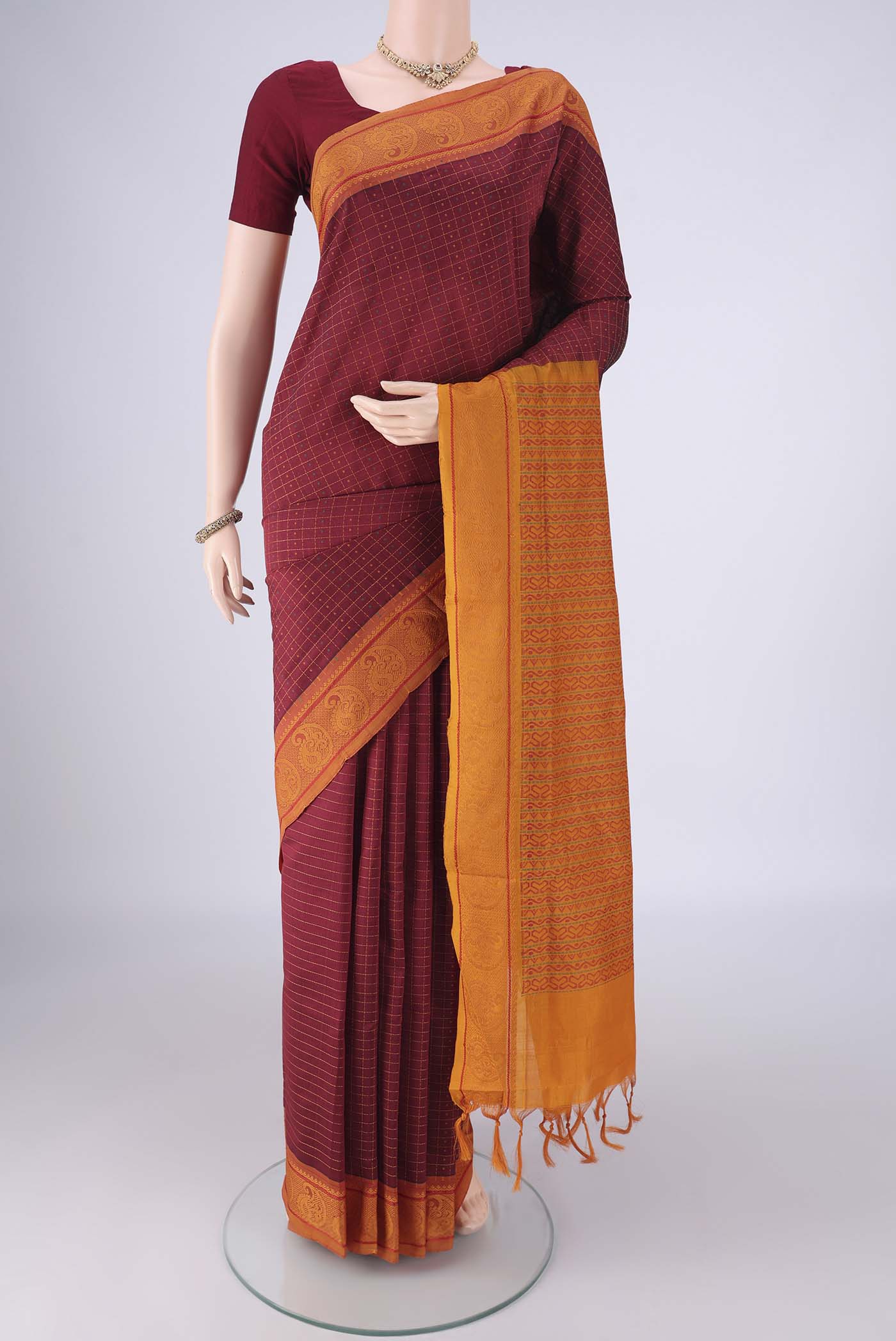 Maroon Poly Cotton Saree with Checked design on the body and Thread Border.  displayed on a mannequin
