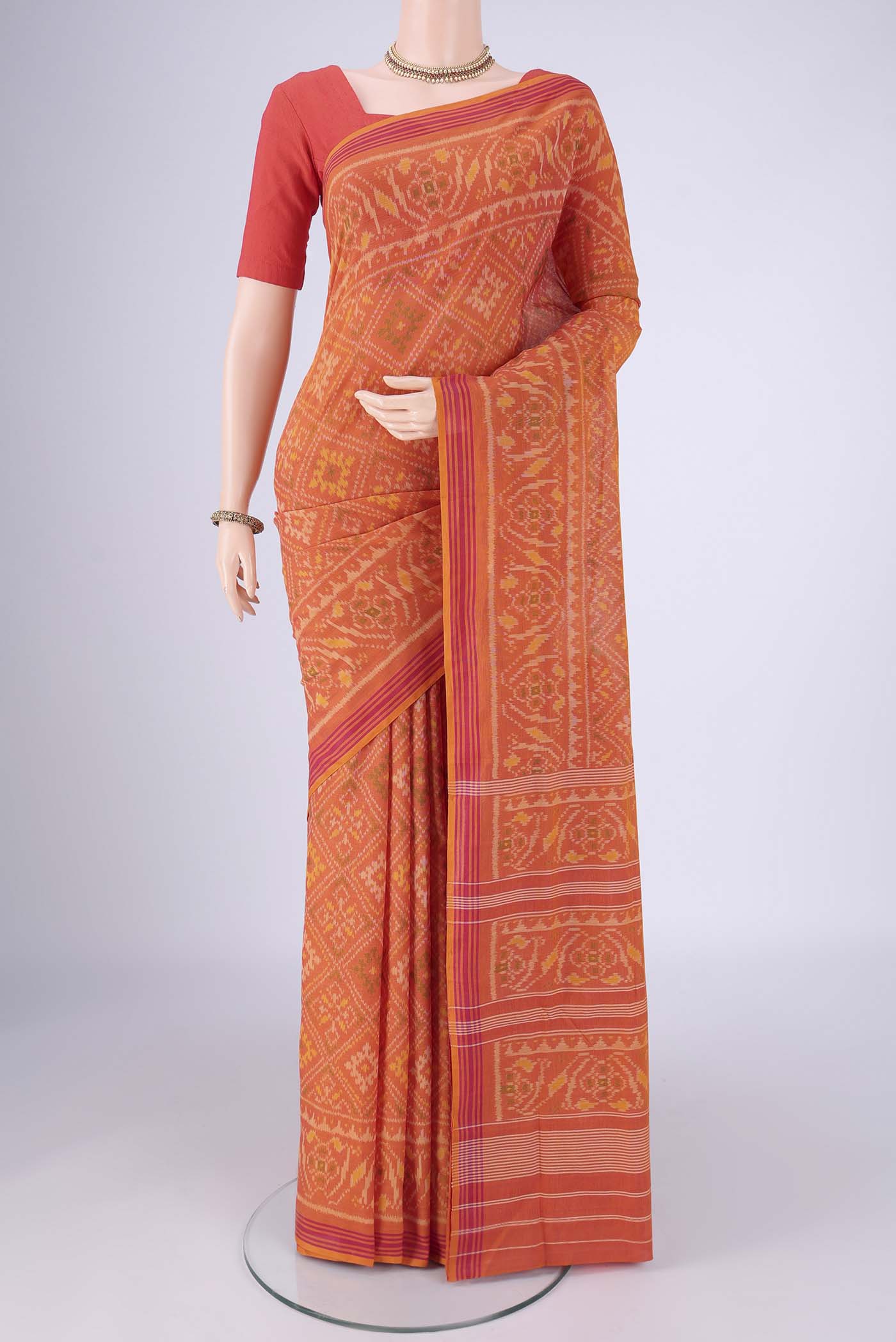 Brick Orange Pochampally Cotton Saree with Pure Ikat on the body and Ikat Border.  displayed on a mannequin